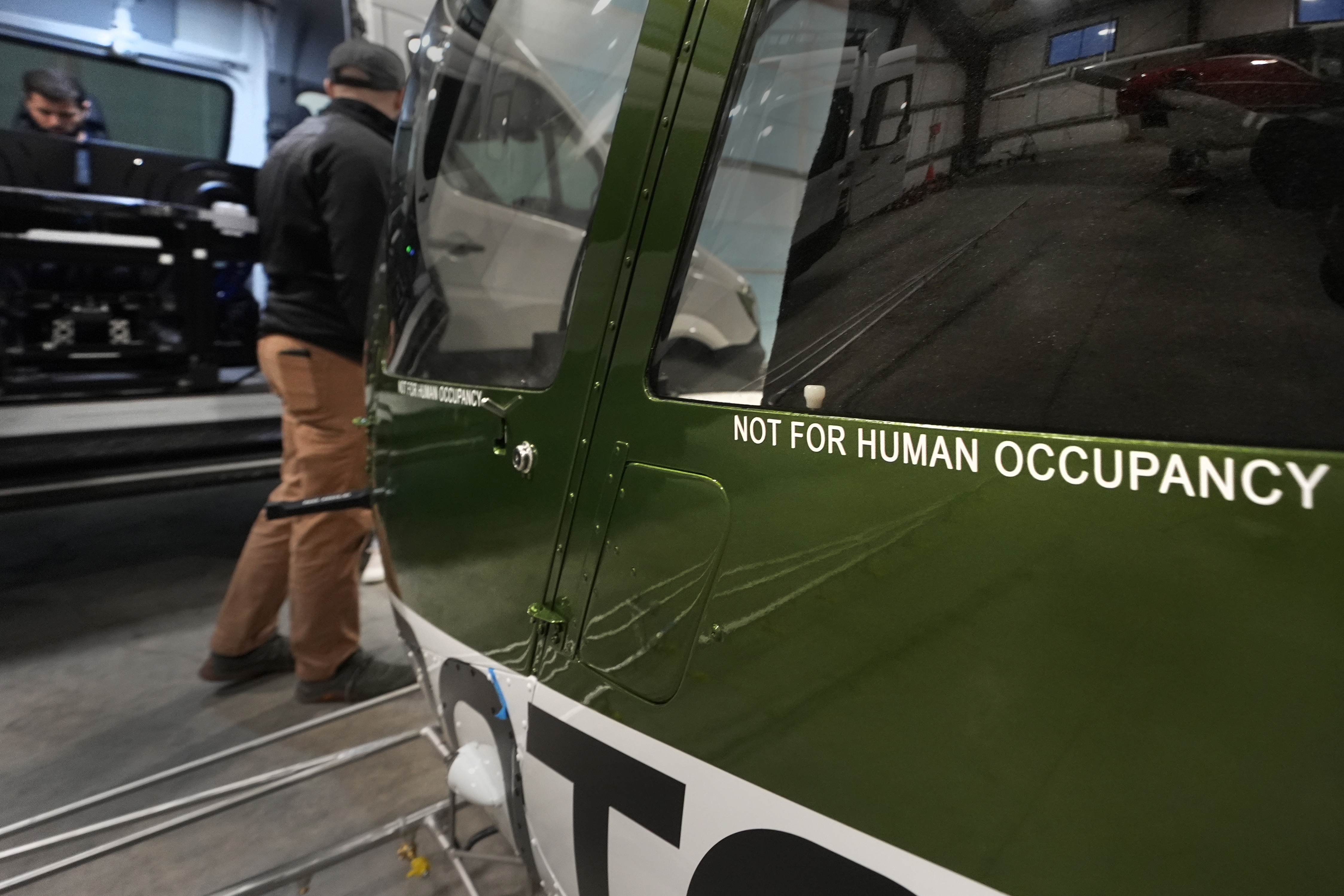 Test pilot Joao Magioni, seated left, talks with production manager Brett Worden while preparing a flight of a Rotor Technologies unmanned semi-autonomous helicopter in a hanger at Intervale Airport, Monday, Nov. 11, 2024, in Henniker, N.H. (AP Photo/Charles Krupa)