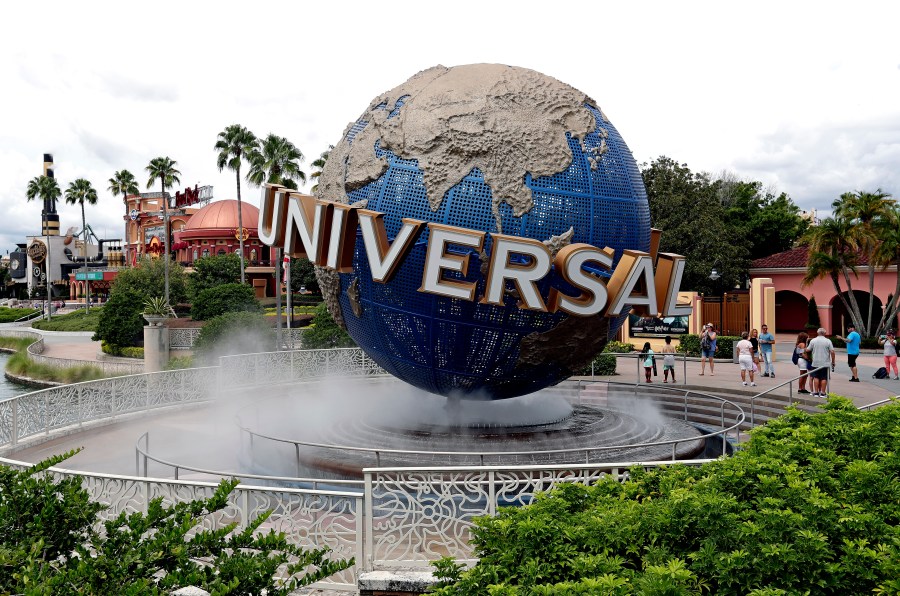 FILE - Guests cool off under a water mist by the globe at Universal Studios City Walk at Universal Studios Florida in Orlando, Fla., Aug. 5, 2019. (AP Photo/John Raoux, File)