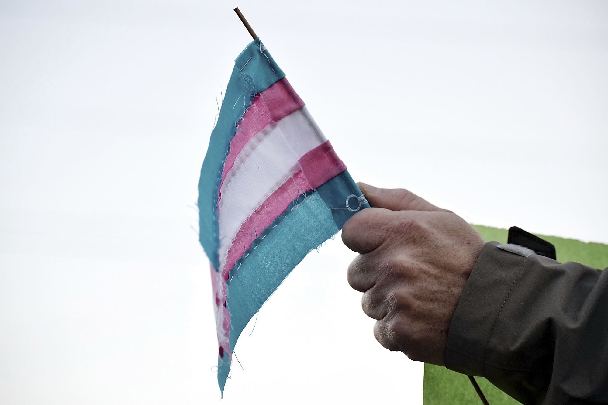 FILE - A person holds a transgender flag to show their support for the transgender community during the sixth annual Transgender Day of Remembrance at Maryville College, Nov. 20, 2016, in Maryville, Tenn. (Brianna Bivens/The Daily Times via AP, File)