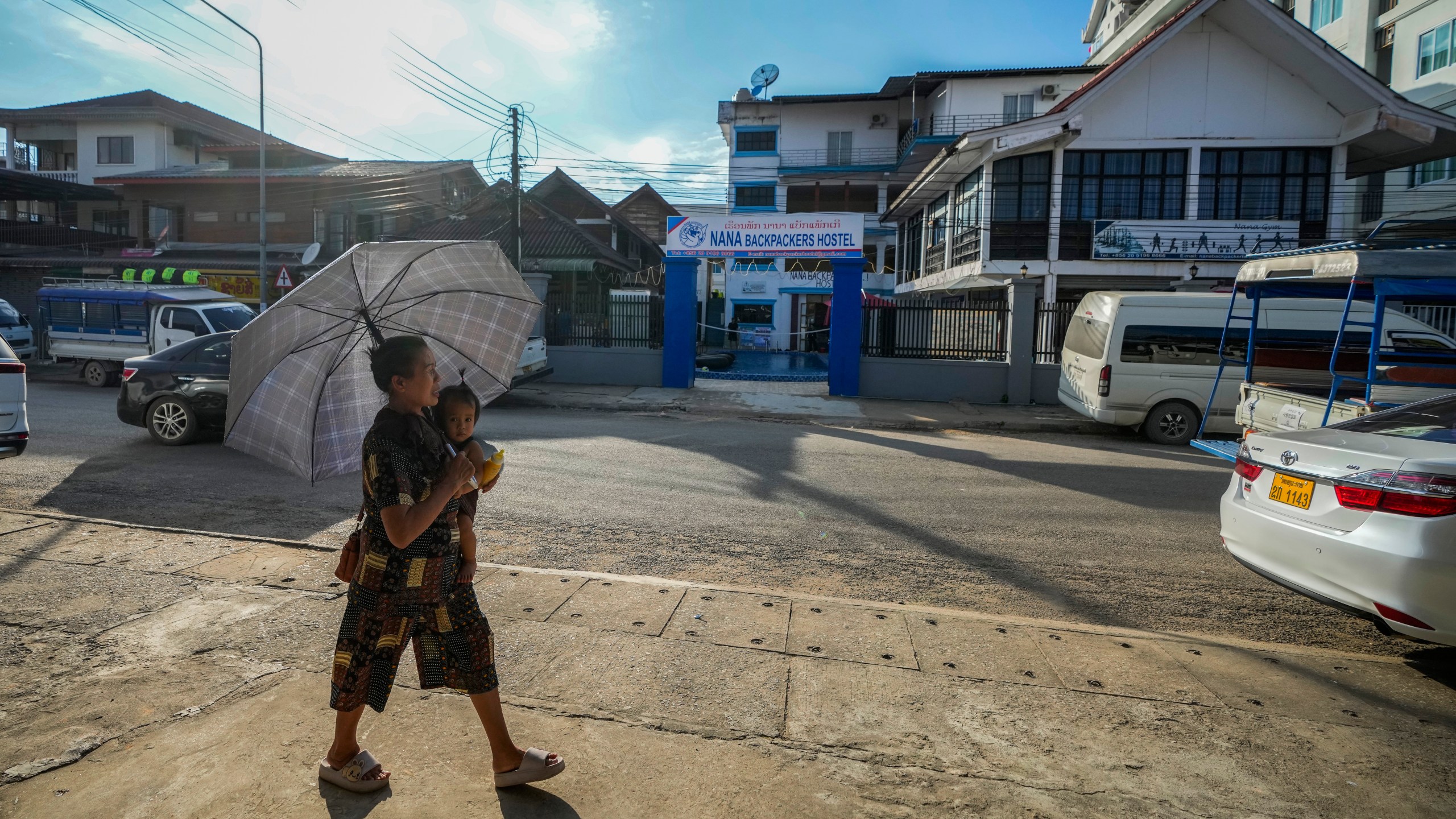 A woman carries a baby as she walks by the Nana Backpack hostel in Vang Vieng, Laos, Tuesday, Nov. 19, 2024. (AP Photo/Anupam Nath)