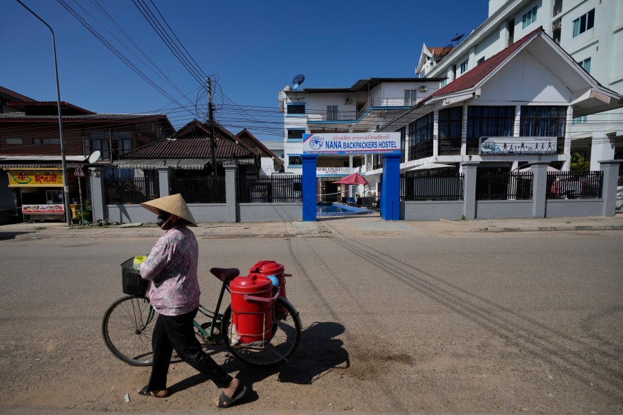 A woman with a bicycle walks pasts Nana Backpackers hostel in Vang Vieng, Laos, Friday, Nov. 22, 2024. (AP Photo/Anupam Nath)