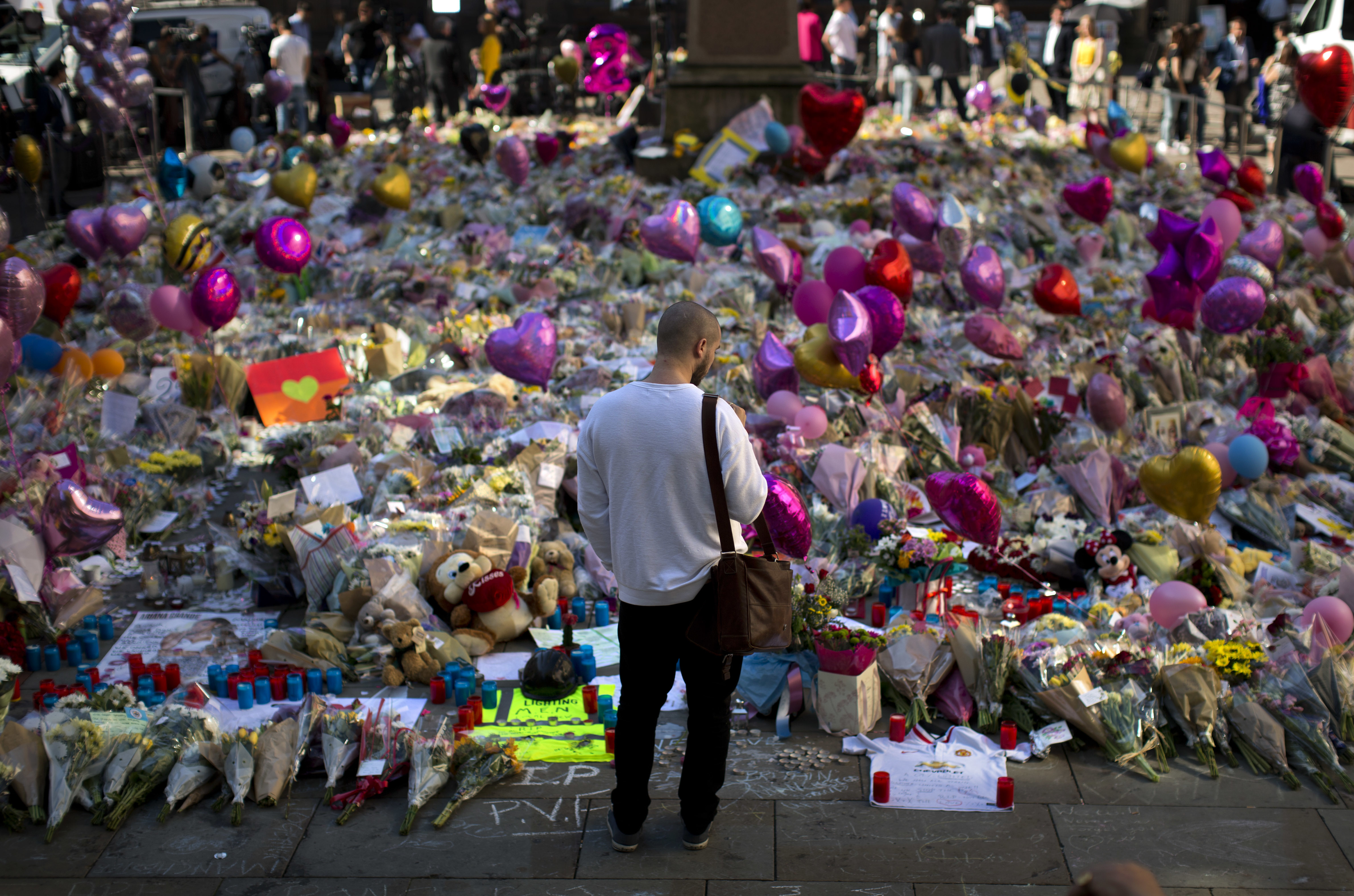 FILE - A man stands next to flowers for the victims of a bombing at St. Ann's Square in central Manchester, England, May 26, 2017. (AP Photo/Emilio Morenatti, File)