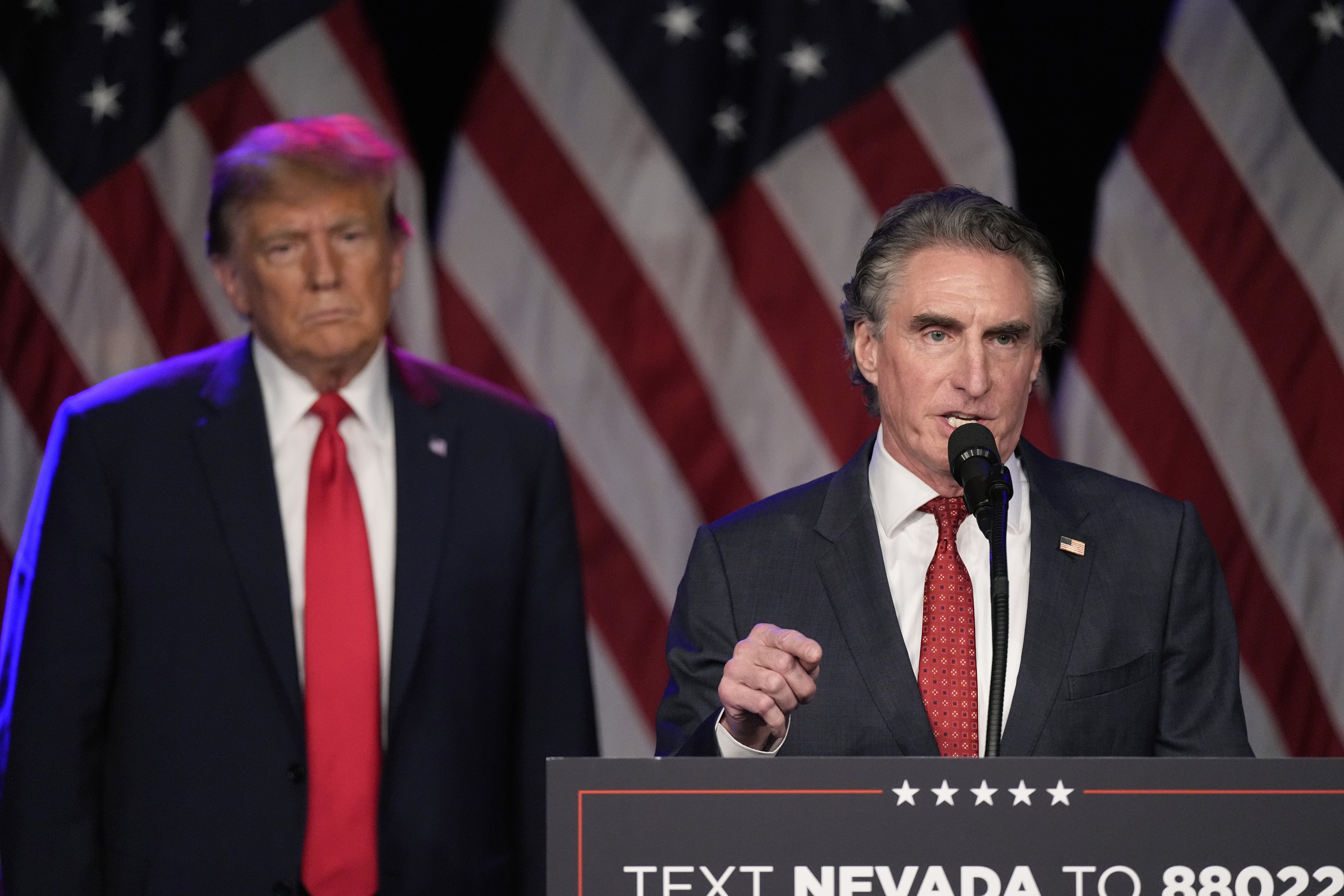 FILE - Republican presidential candidate former President Donald Trump listens as North Dakota Gov. Doug Burgum speaks at a caucus night rally in Las Vegas, Feb. 8, 2024. (AP Photo/Mark J. Terrill, File)