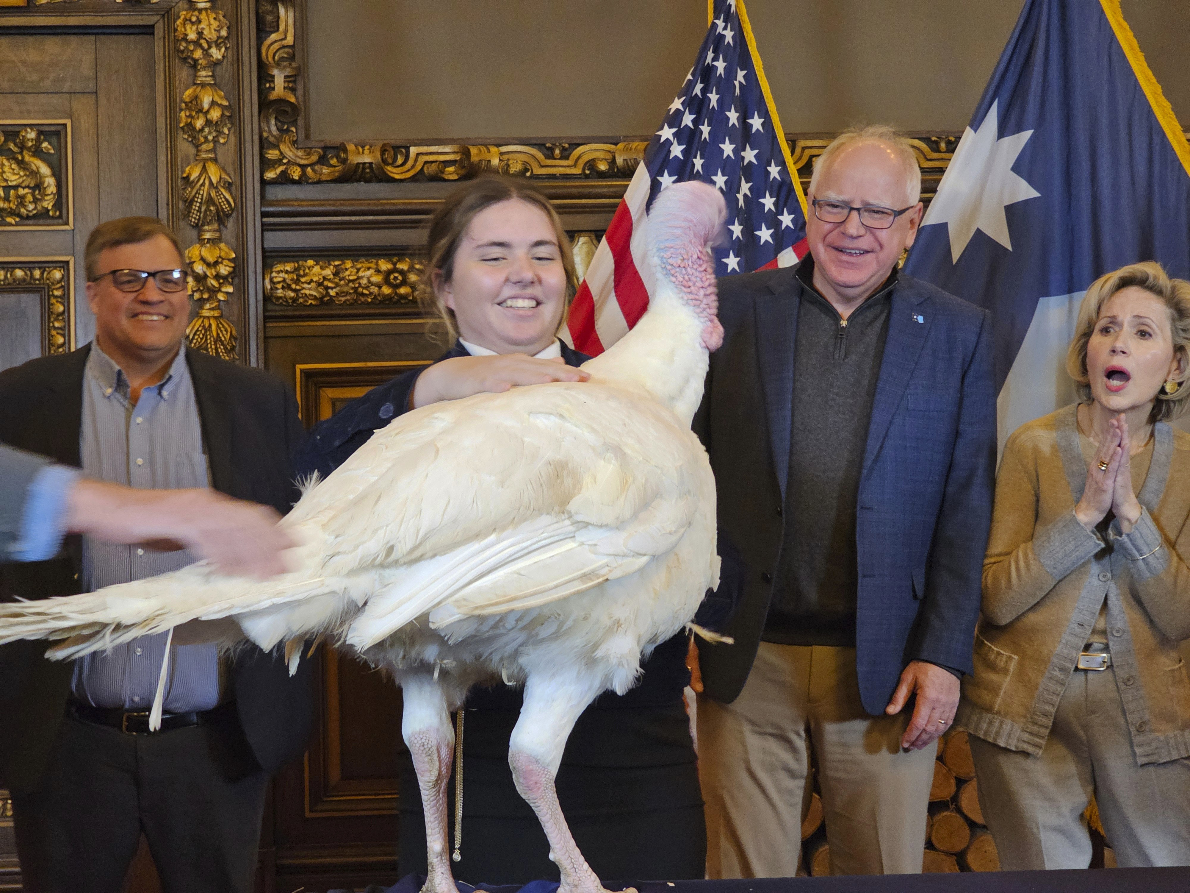 Gov. Tim Walz, second right, accepts the symbolic presentation of a turkey from Paisley VonBerge, a Future Farmers of America leader from Hutchinson, at the Minnesota State Capitol on Tuesday, Nov. 26, 2024, as state Agriculture Commissioner Thom Petersen and first lady Gwen Walz look on. (AP Photo/Steve Karnowski)