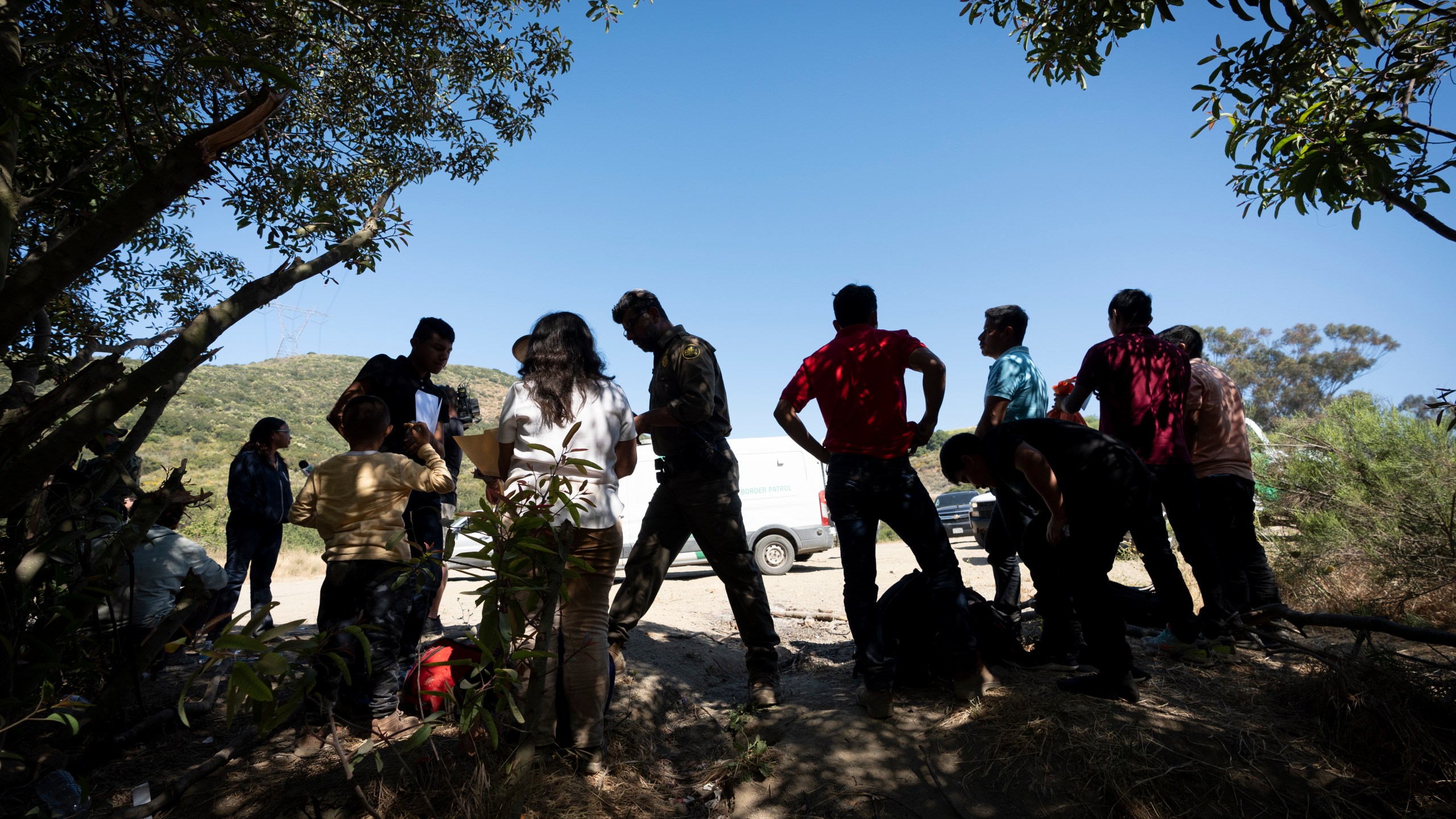 FILE - Border Patrol agents talk with migrants seeking asylum as they prepare them for transportation to be processed, June 5, 2024, near Dulzura, Calif. (AP Photo/Gregory Bull, File)