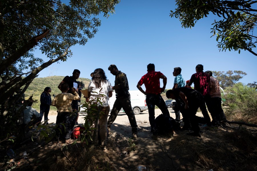 FILE - Border Patrol agents talk with migrants seeking asylum as they prepare them for transportation to be processed, June 5, 2024, near Dulzura, Calif. (AP Photo/Gregory Bull, File)