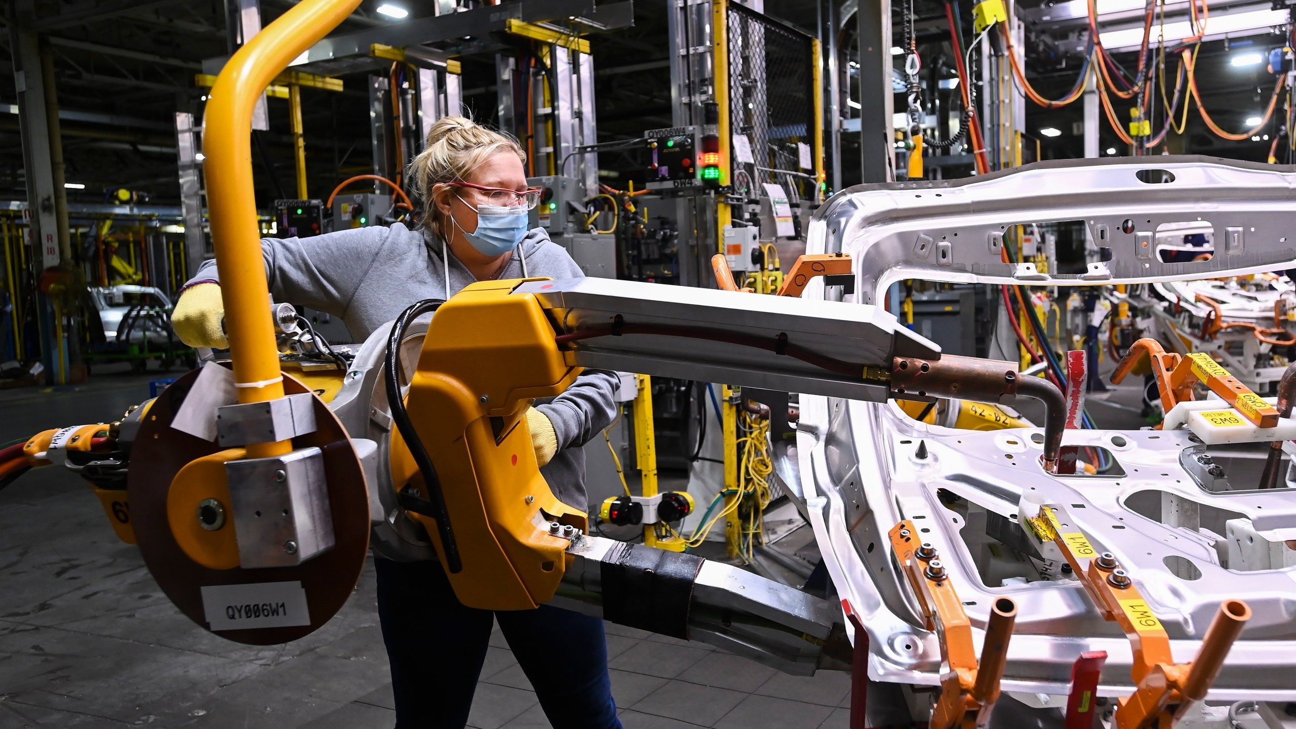 FILE - GM workers use human assistance automation to weld vehicle doors at the General Motors assembly plant during the COVID-19 pandemic in Oshawa, Ontario, March 19, 2021. (Nathan Denette/The Canadian Press via AP, File)