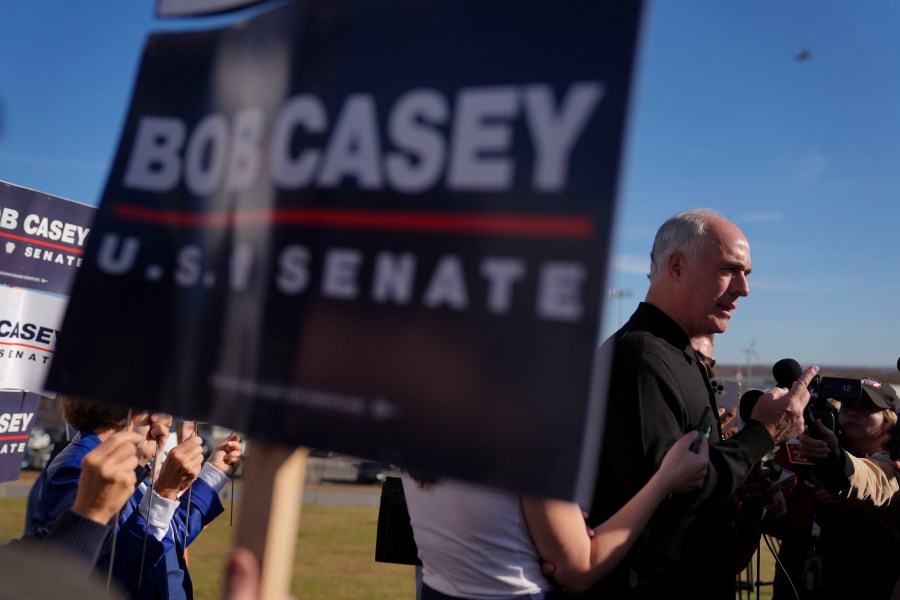 FILE - Sen. Bob Casey, D-Pa., left, stops to speak to members of the media before voting, Tuesday, Nov. 5, 2024, in Scranton, Pa. (AP Photo/Matt Rourke, File)