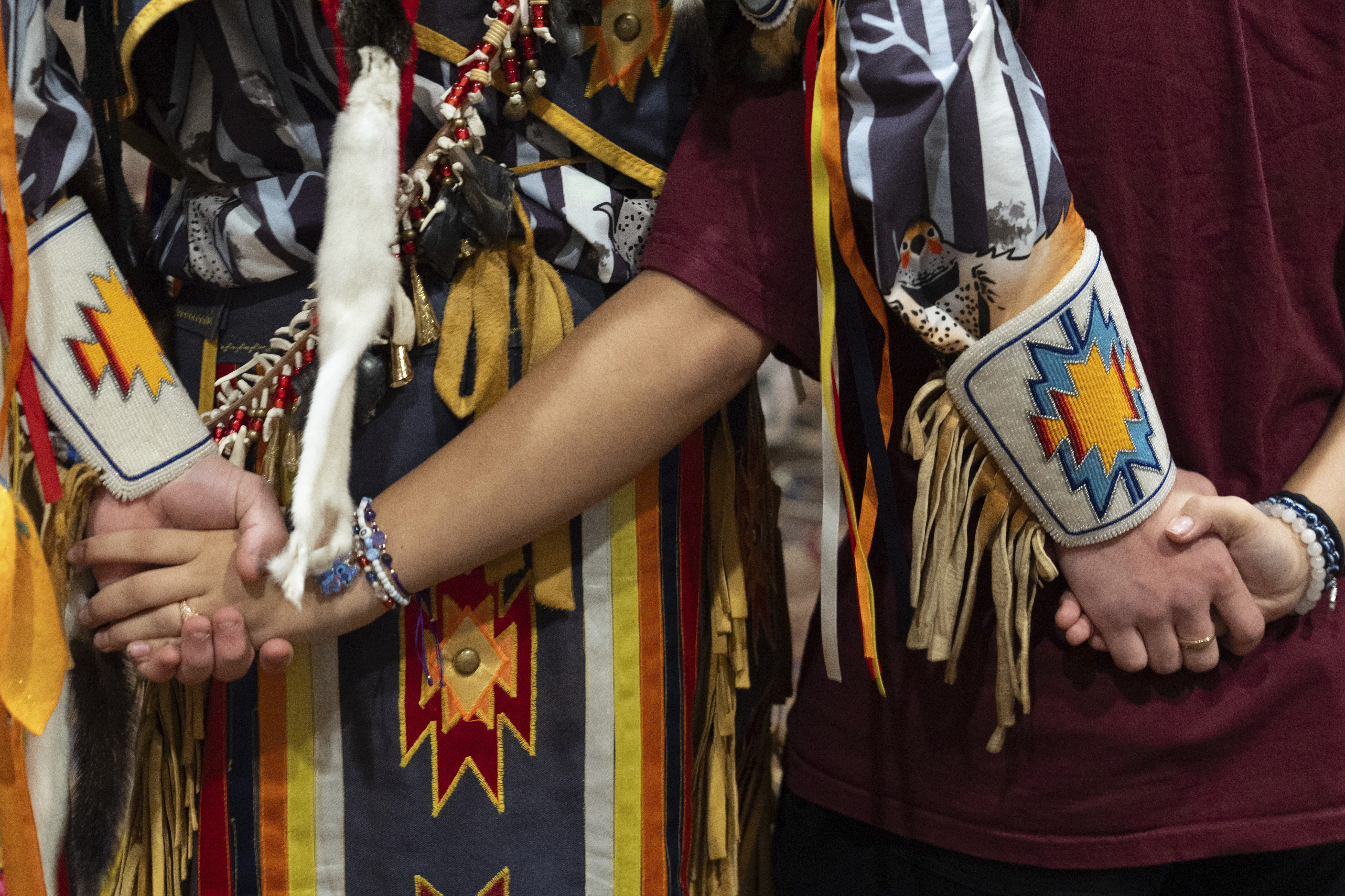 People hold hands during a dance at a powwow at Chinook Winds Casino Resort, Saturday, Nov. 16, 2024, in Lincoln City, Ore. (AP Photo/Jenny Kane)