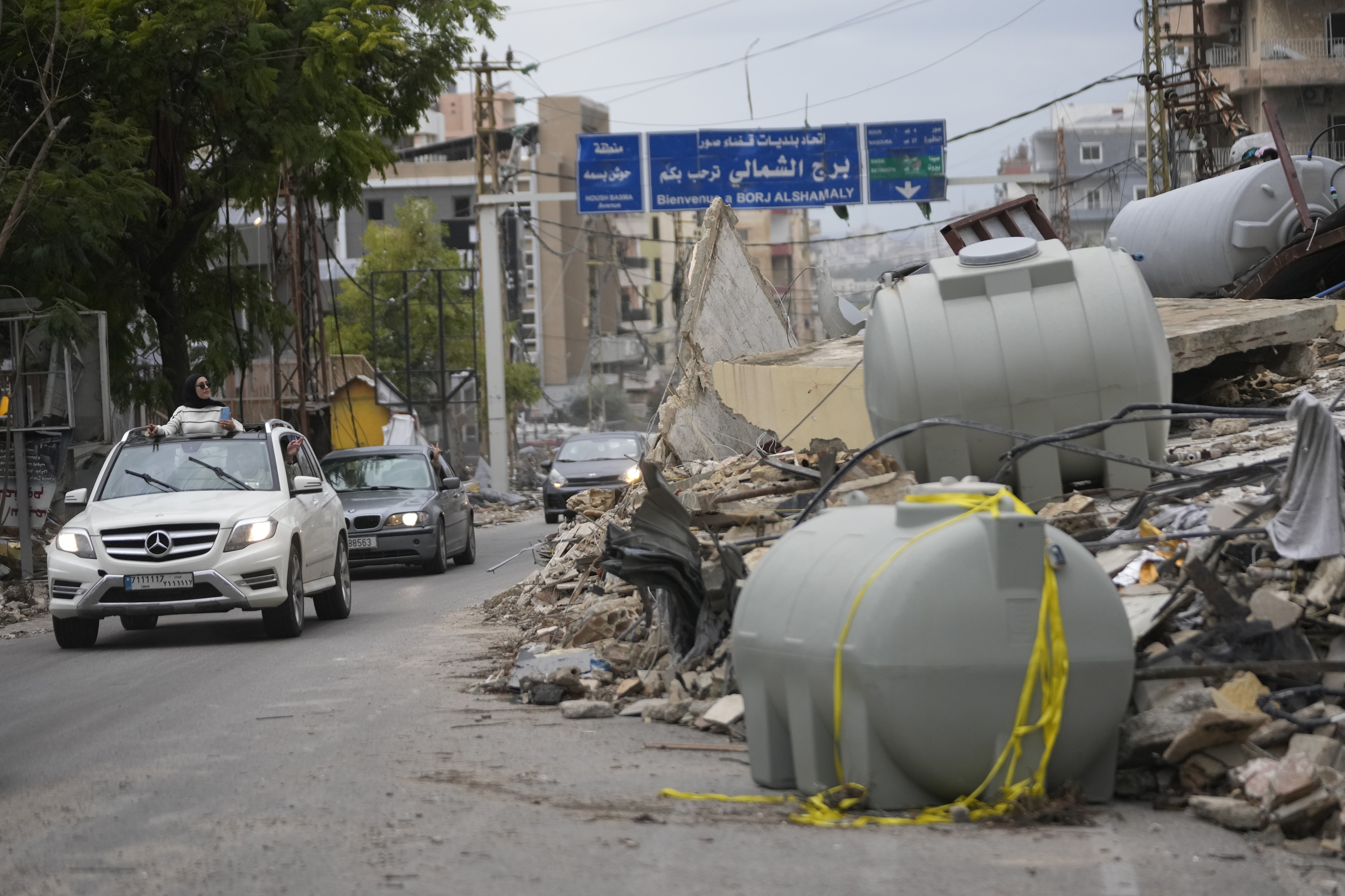 Displaced residents drive past the rubble of a destroyed building as they return to their villages, following a ceasefire between Israel and Hezbollah, Wednesday, Nov. 27, 2024, in Tyre, southern Lebanon. (AP Photo/Hussein Malla)