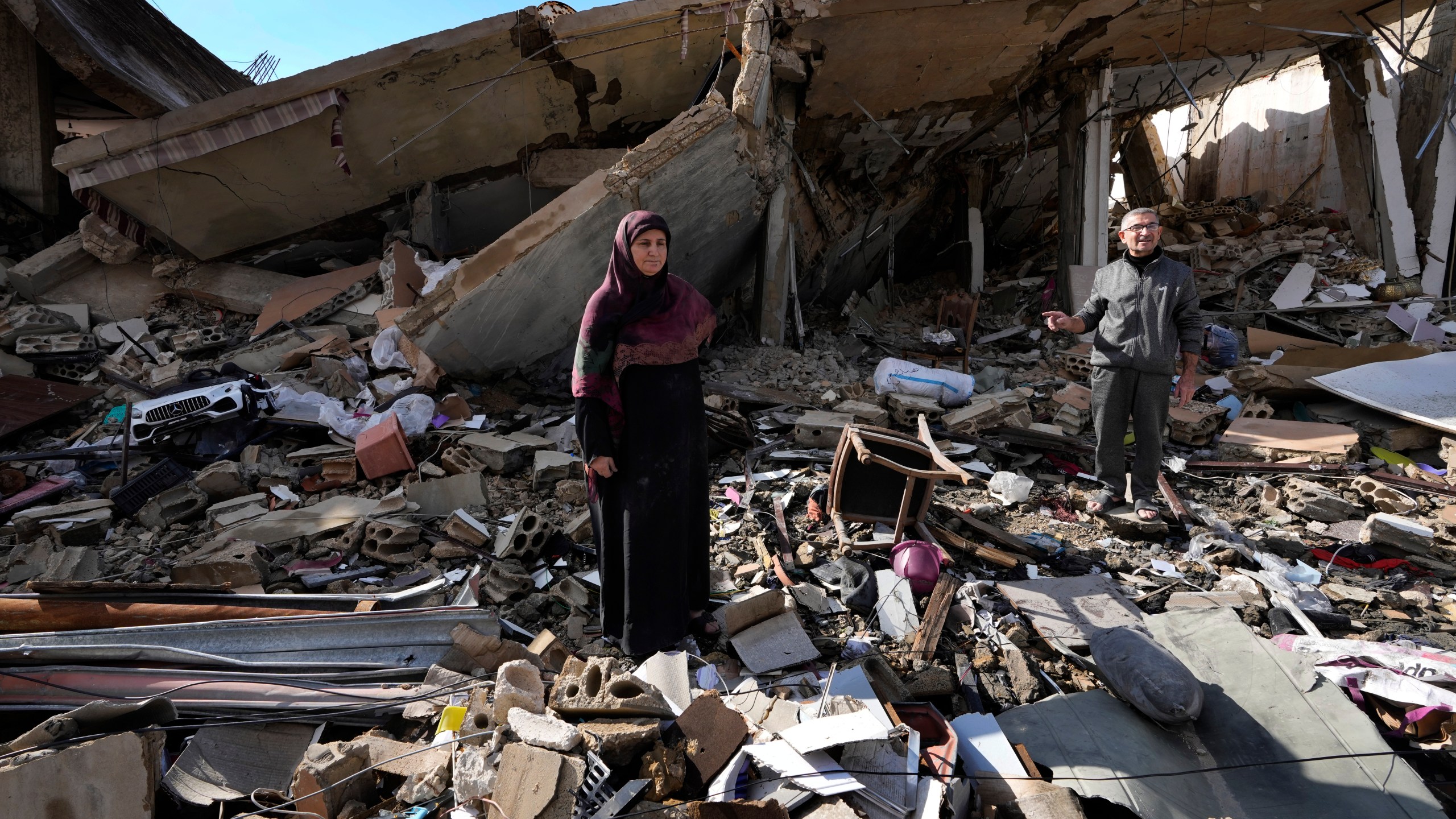 Mariam Kourani, 56, and her husband Ali Haidous, stand on the rubble of their destroyed house after they returned to their village of Hanouiyeh , southern Lebanon, Thursday, Nov. 28, 2024 following a ceasefire between Israel and Hezbollah that went into effect on Wednesday.(AP Photo/Hussein Malla)