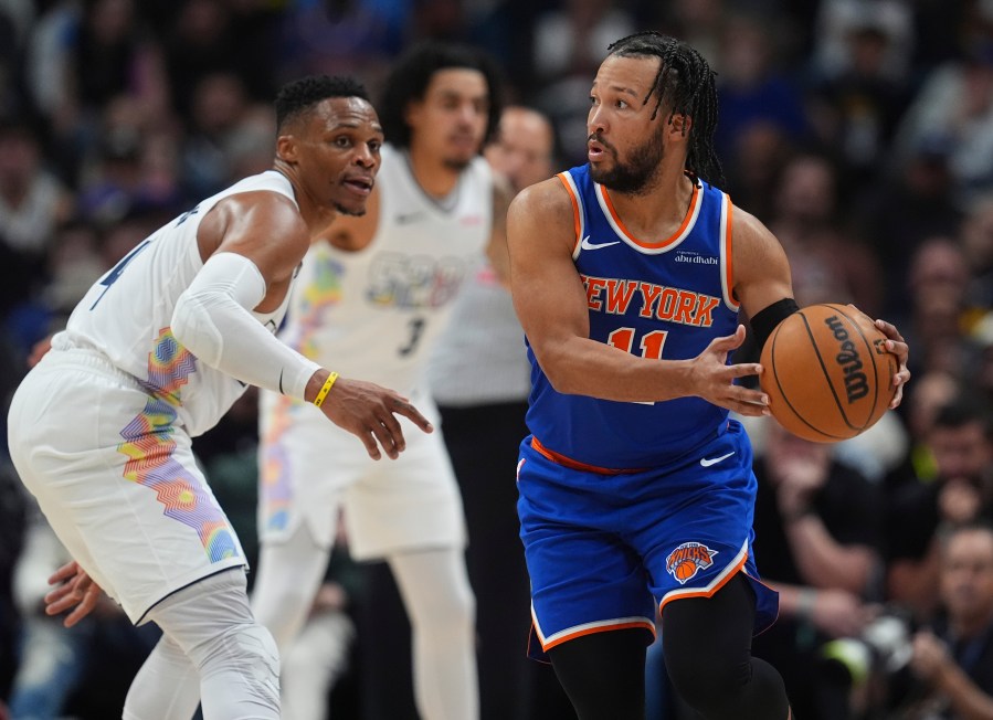 New York Knicks guard Jalen Brunson, right, looks to pass the ball as Denver Nuggets guard Russell Westbrook defends in the second half of an NBA basketball game Monday, Nov. 25, 2024, in Denver. (AP Photo/David Zalubowski)