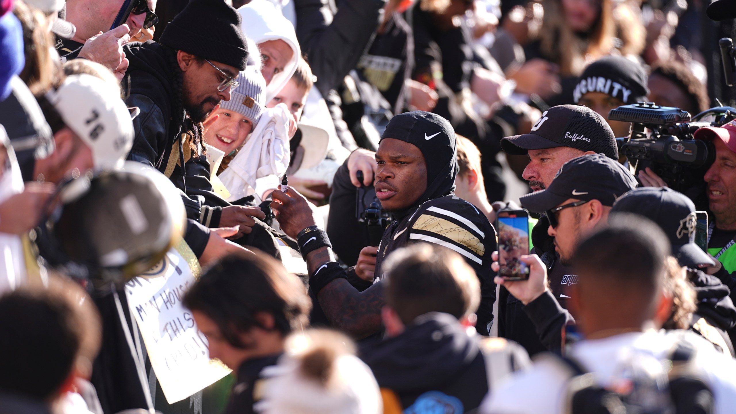 Colorado wide receiver Travis Hunter, center, is surrounded by fans as he heads to the locker room after an NCAA college football game against Oklahoma State, Friday, Nov. 29, 2024, in Boulder, Colo. (AP Photo/David Zalubowski)