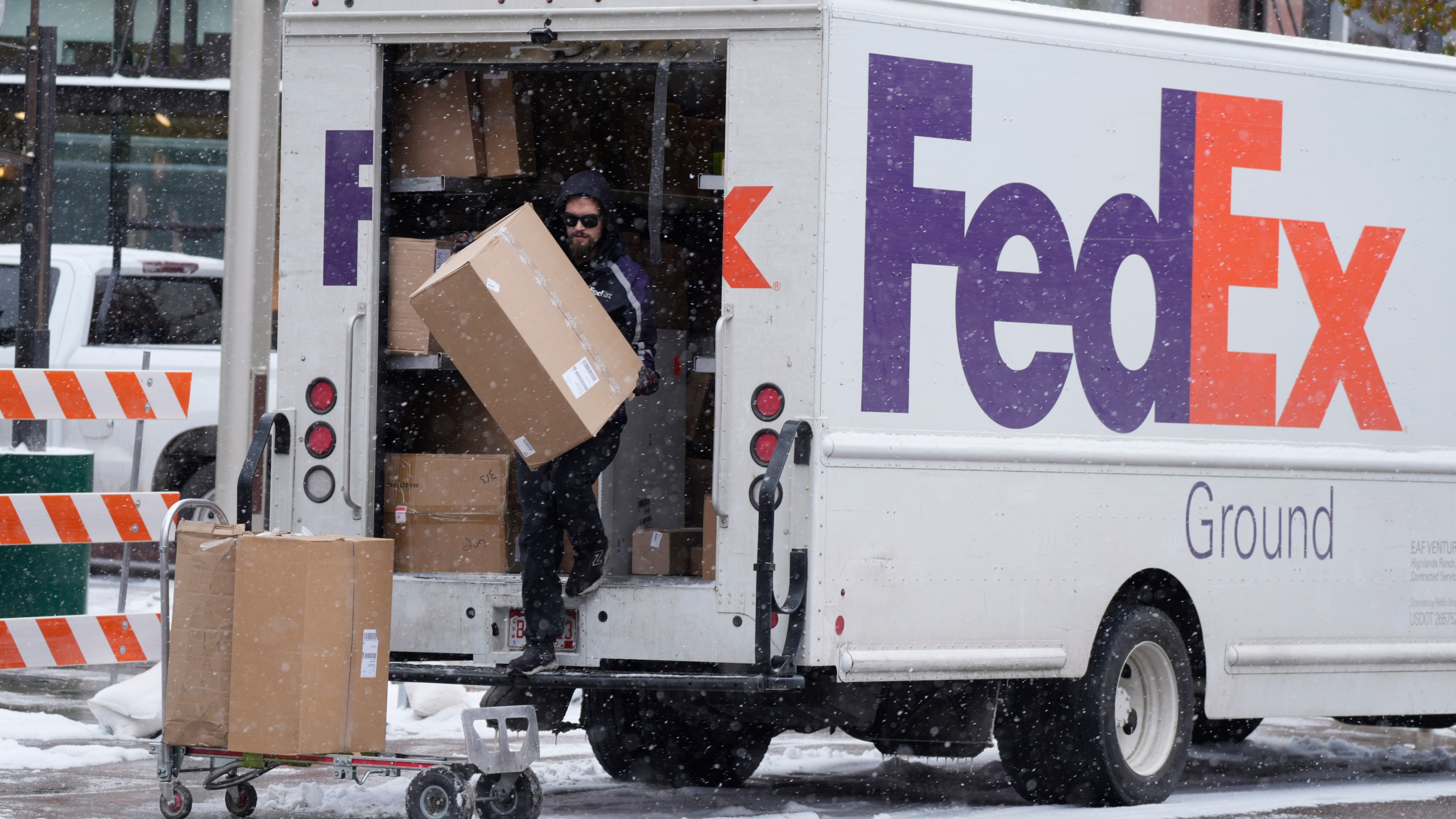 FILE - A FedEx delivery person carries a package from a truck on Nov. 17, 2022, in Denver. (AP Photo/David Zalubowski, File)