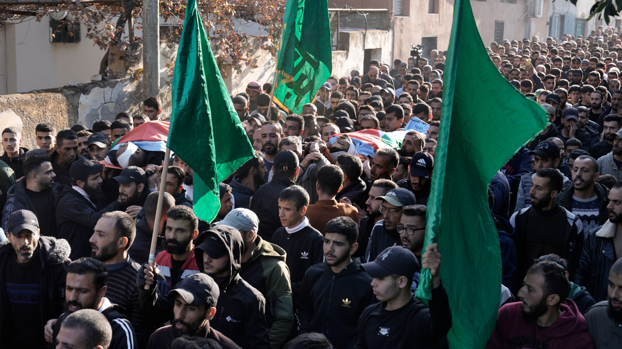 Mourners carry Hamas flags and the bodies, wrapped with the Palestinian flag, of Akram Abu Arrah and Mohammad Ghannam, both killed in an airstrike Israel said targeted a militant cell, during their funeral in the West Bank village of Al-Aqaba, Tuesday Dec. 3, 2024. (AP Photo/Majdi Muhammad)