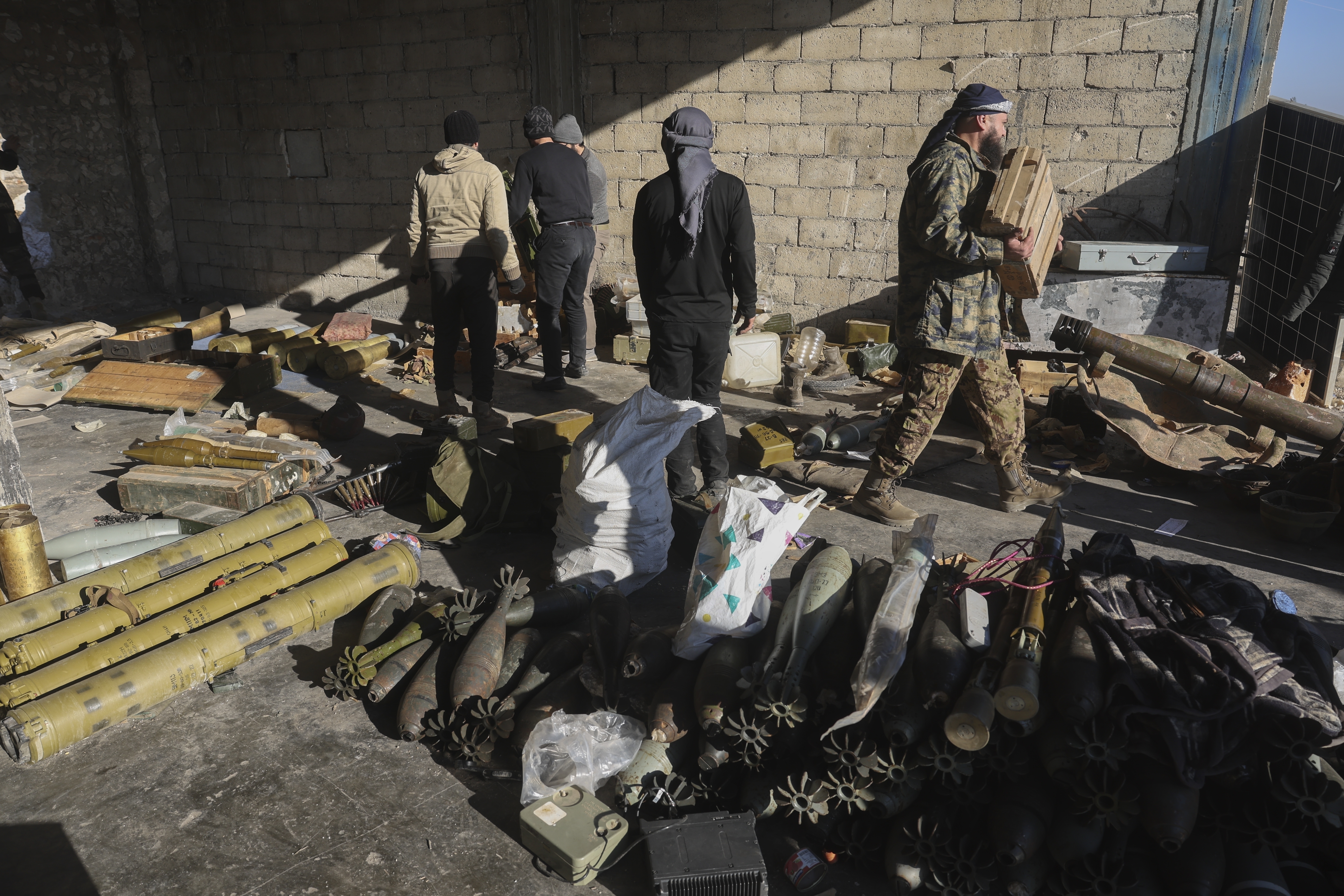 Syrian opposition fighters seize ammunition abandoned by the army in the town of Khan Assubul, Syria, southwest of Aleppo, Sunday, Dec. 1, 2024. Insurgents launched a two-pronged attack on Aleppo and the countryside around Idlib. (AP Photo/Ghaith Alsayed)