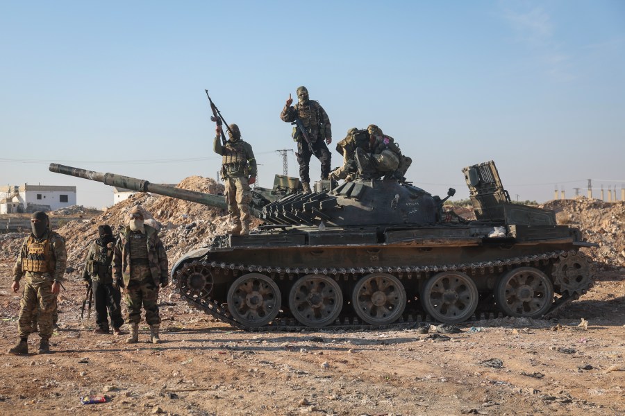 Syrian opposition fighters stand atop a seized Syrian army armoured vehicle in the outskirts of Hama, Syria, Tuesday Dec. 3, 2024. (AP Photo/Ghaith Alsayed)