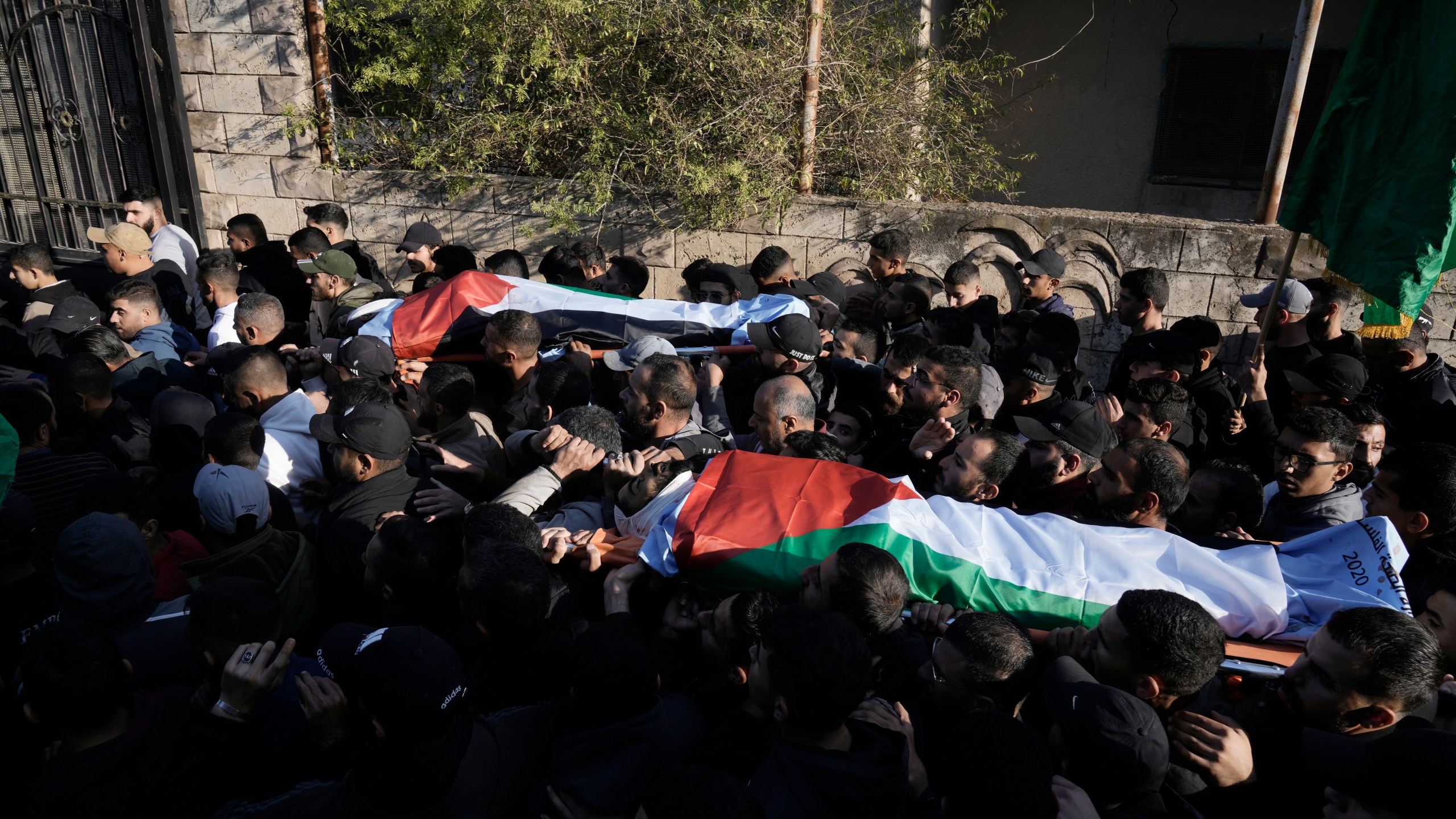 Mourners carry the bodies wrapped with the Palestinian flag, of Akram Abu Arrah and Mohammad Ghannam, both killed in an airstrike Israel said targeted a militant cell, during their funeral in the West Bank village of Al-Aqaba, Tuesday Dec. 3, 2024. (AP Photo/Majdi Muhammad)