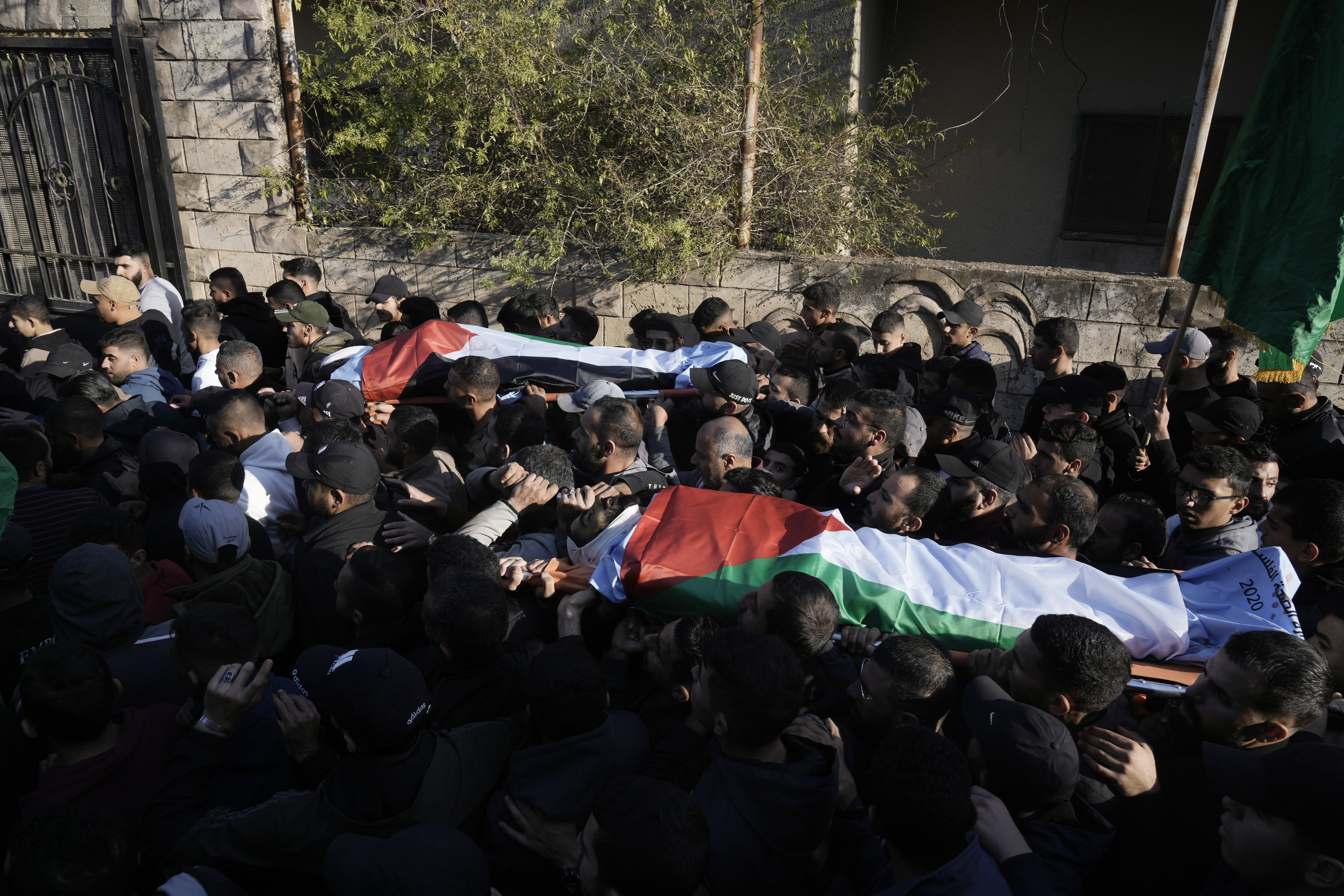 Mourners carry the bodies wrapped with the Palestinian flag, of Akram Abu Arrah and Mohammad Ghannam, both killed in an airstrike Israel said targeted a militant cell, during their funeral in the West Bank village of Al-Aqaba, Tuesday Dec. 3, 2024. (AP Photo/Majdi Muhammad)