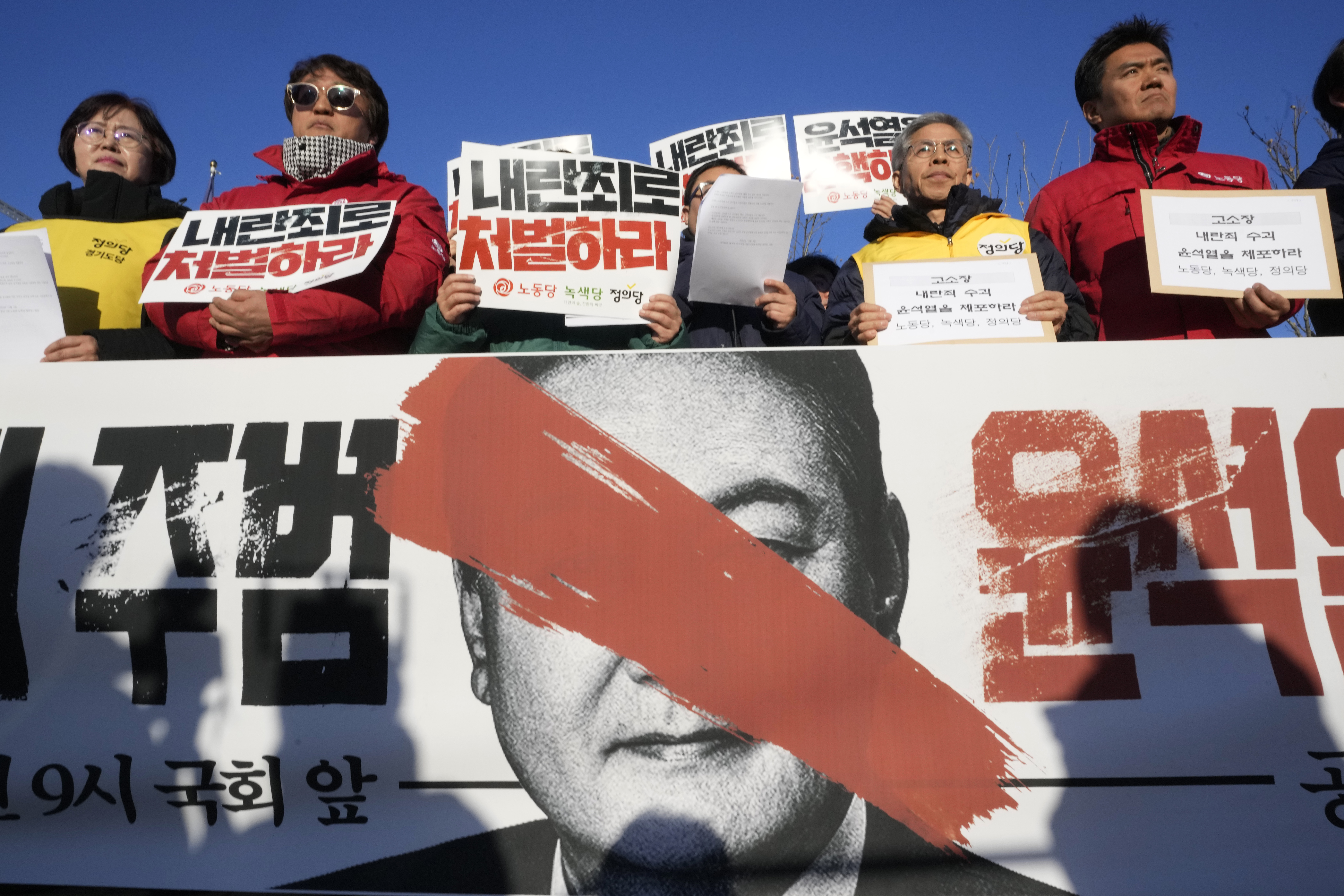 Protesters stage a rally to demand South Korean President Yoon Suk Yeol to step down in front of the National Assembly in Seoul, South Korea, Wednesday, Dec. 4, 2024. The signs read "Punish." (AP Photo/Ahn Young-joon)