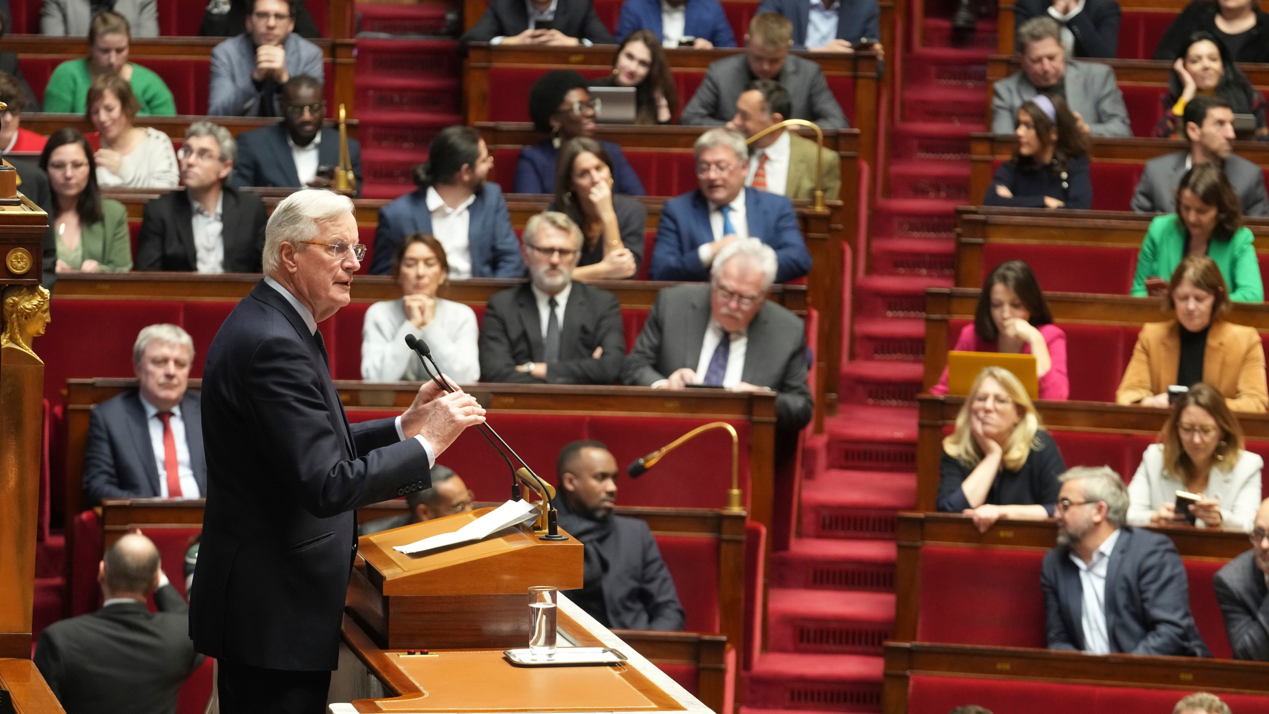 French Prime Minister Michel Barnier delivers his speech at the National Assembly while France's minority government may be on its last legs as opposition lawmakers moved this week toward a no-confidence vote, Monday, Dec. 2, 2024 in Paris. (AP Photo/Michel Euler)