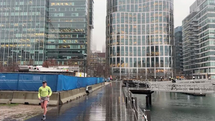 A jogger runs along the harbor as rain falls in Boston’s Seaport neighborhood on Wednesday Dec 11, 2024. (AP Photo/Michael Casey)