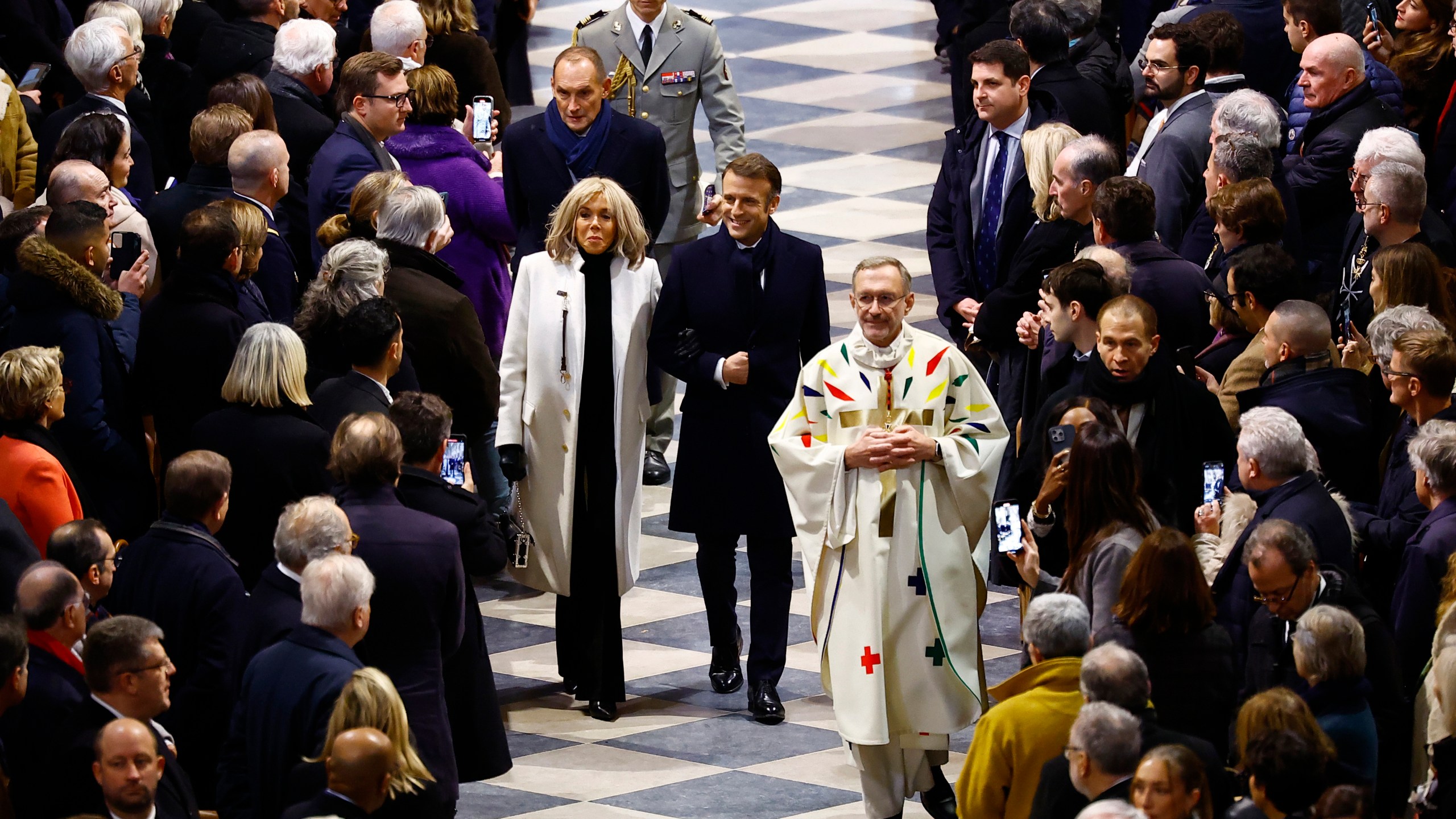 FILE - French President Emmanuel Macron, center, and his wife Brigitte Macron arrive to attend the inaugural Mass, with the consecration of the altar, at the Notre Dame Cathedral, five-and-a-half years after a fire ravaged the Gothic masterpiece, as part of ceremonies to mark the Cathedral's reopening after its restoration, in Paris, France, Sunday, Dec. 8, 2024. (Sarah Meyssonnier/Pool Photo via AP)