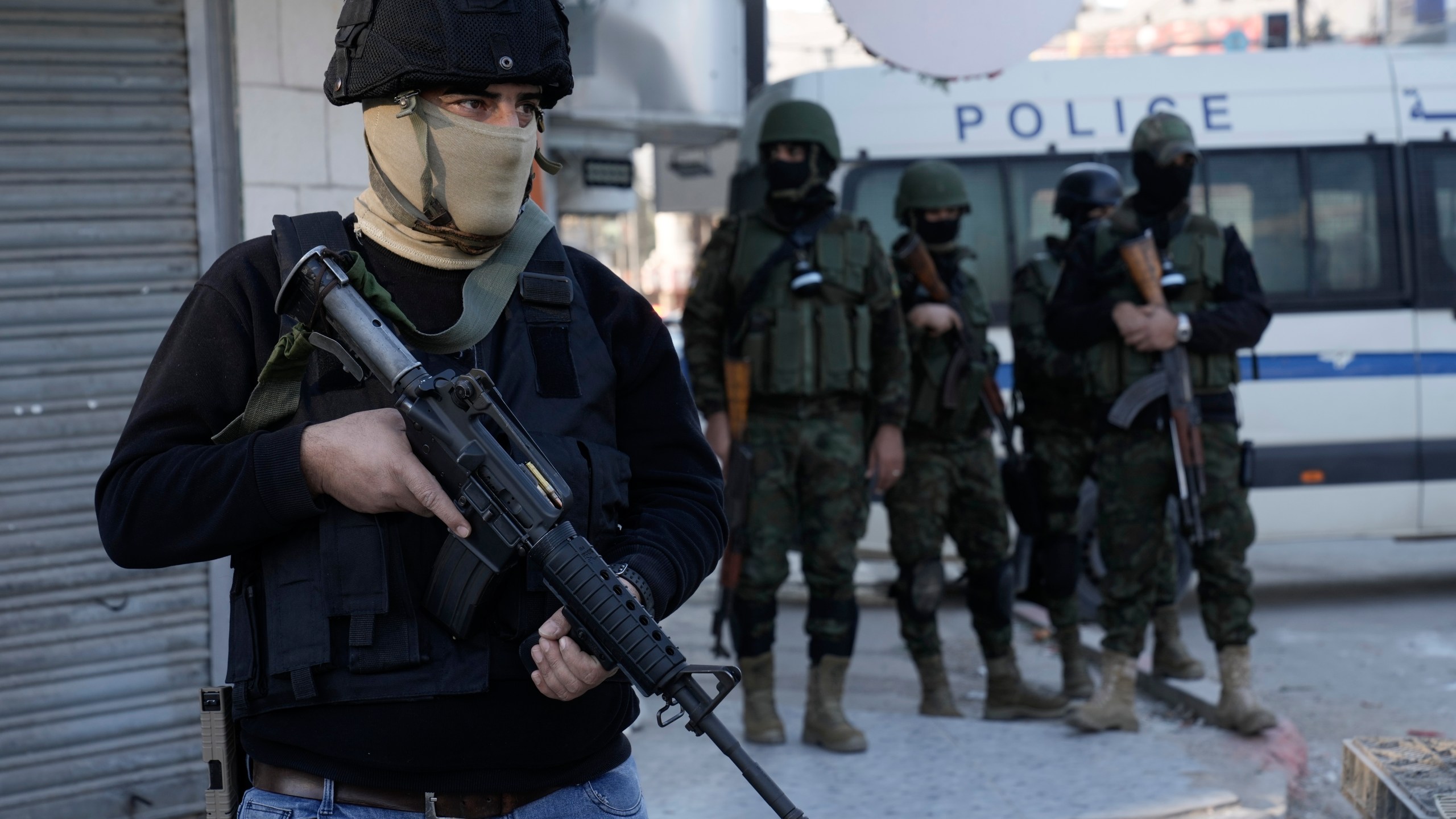 A officer from the Palestinian Authority clutches his gun as Palestinian security forces mount a major raid against militants in the Jenin refugee camp in the Israeli-occupied West Bank, Monday, Dec. 16, 2024.(AP Photo/Majdi Mohammed).