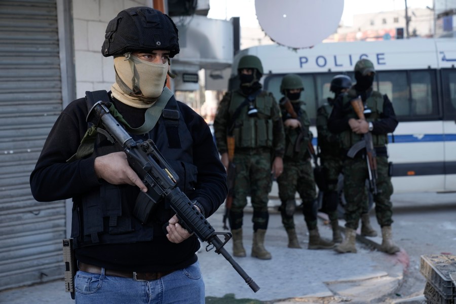 A officer from the Palestinian Authority clutches his gun as Palestinian security forces mount a major raid against militants in the Jenin refugee camp in the Israeli-occupied West Bank, Monday, Dec. 16, 2024.(AP Photo/Majdi Mohammed).