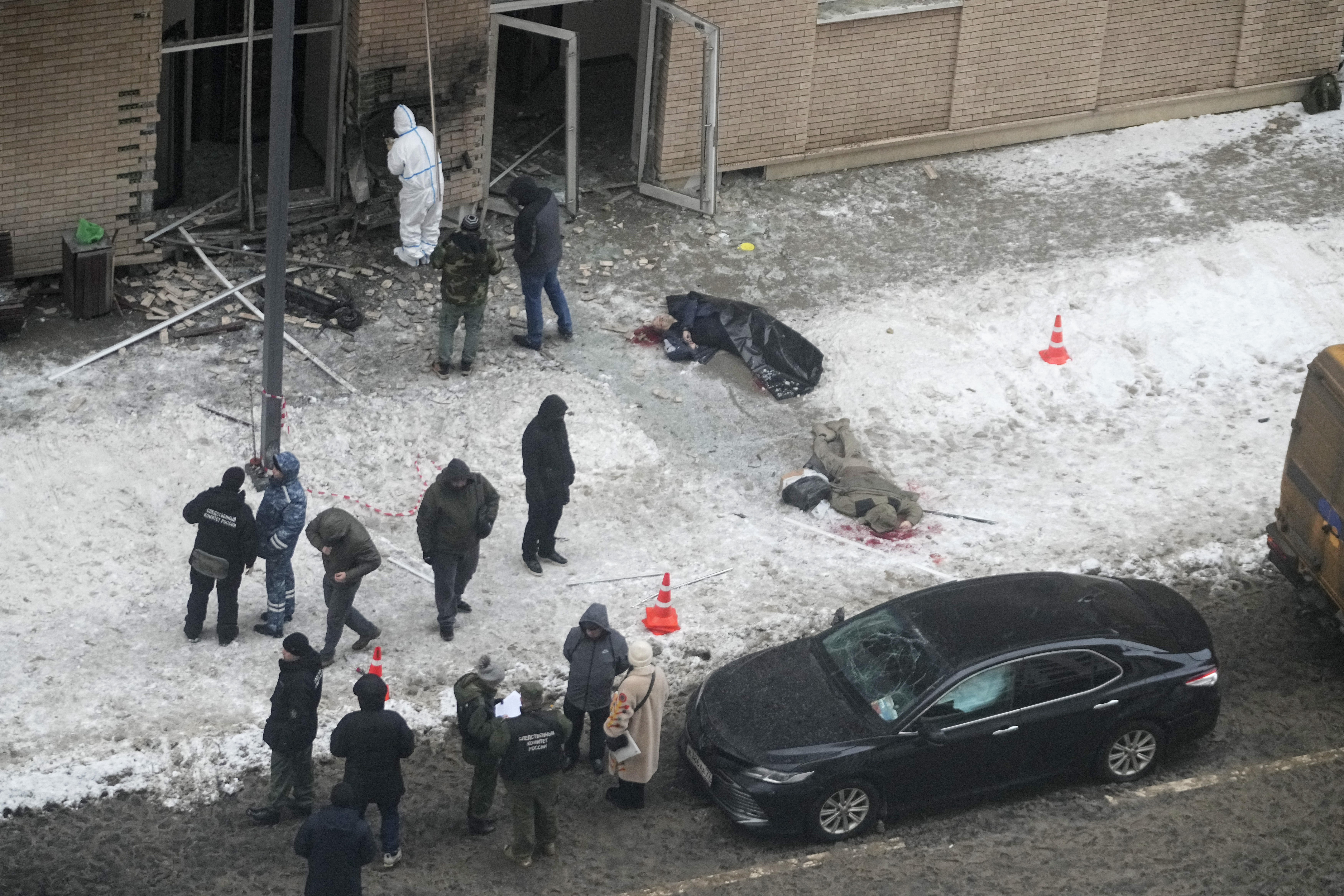 EDS NOTE: GRAPHIC CONTENT - Investigators work at the place where Lt. General Igor Kirillov, center, the head of Russia's Nuclear, Biological, and Chemical Defence Forces and his assistant, right, were killed by an explosive device planted close to a residential apartment's block in Moscow, Russia, Tuesday, Dec. 17, 2024. (AP Photo)