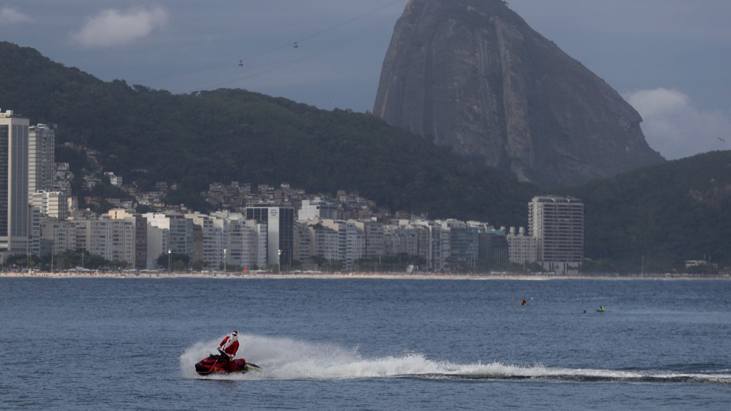 A firefighter dressed as Santa Claus drives a Jet Ski by Copacabana Beach in Rio de Janeiro, Tuesday, Dec. 17, 2024. (AP Photo/Bruna Prado)