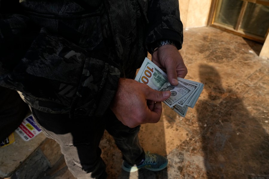 A man poses for a photo without showing his face as he counts U.S. dollars at Ferdowsi street, Tehran's go-to venue for foreign currency exchange, in downtown Tehran, Iran, Wednesday, Dec. 18, 2024. (AP Photo/Vahid Salemi)