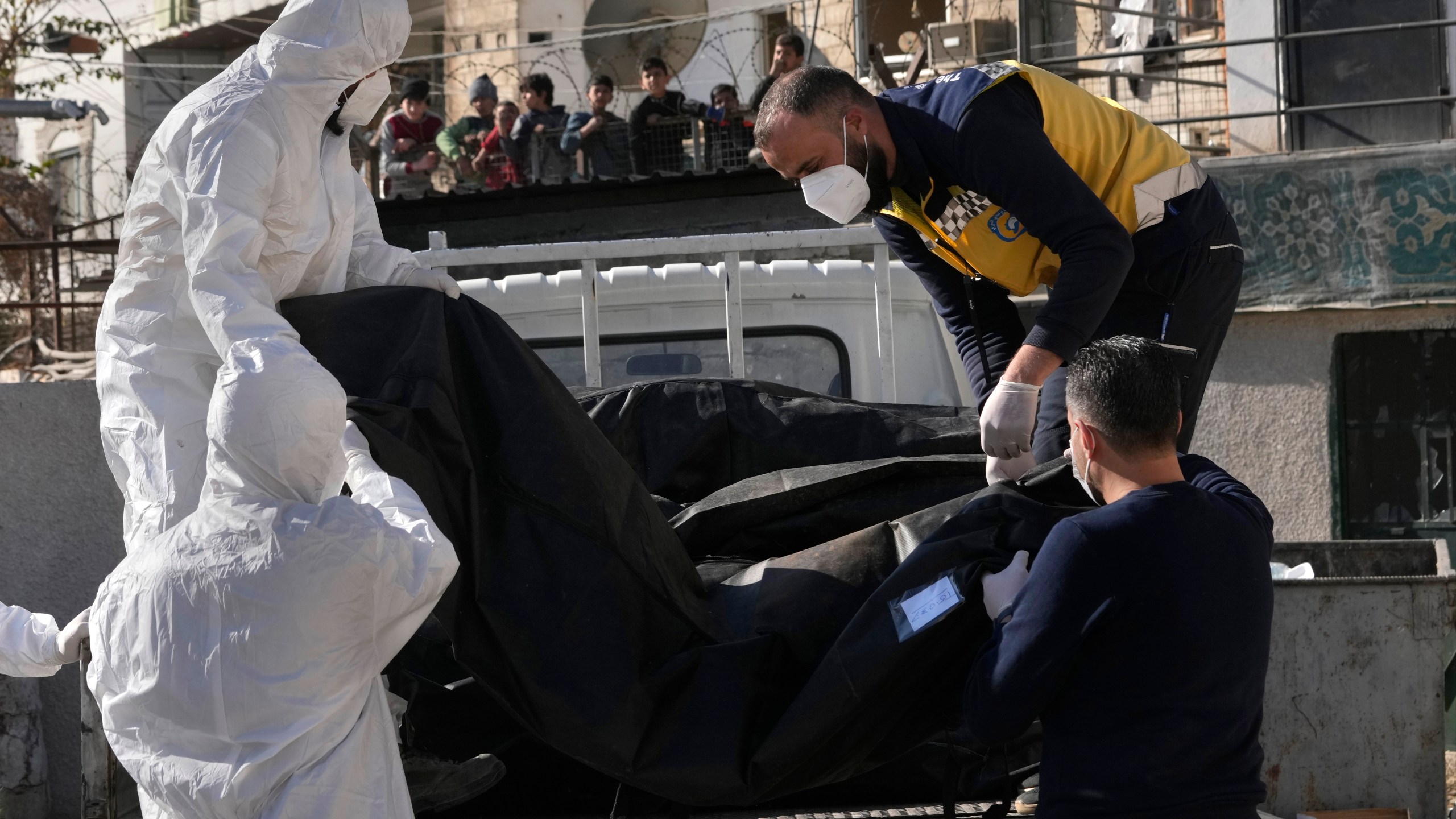 Members of the Syrian civil defense group, known as the White Helmets, put on a truck bodies and human remains after they collect them from a morgue, previously used by pro-government Iranian units, located near the Set Zainab shrine, south of Damascus, Syria, Wednesday, Dec. 18, 2024. (AP Photo/Hussein Malla)