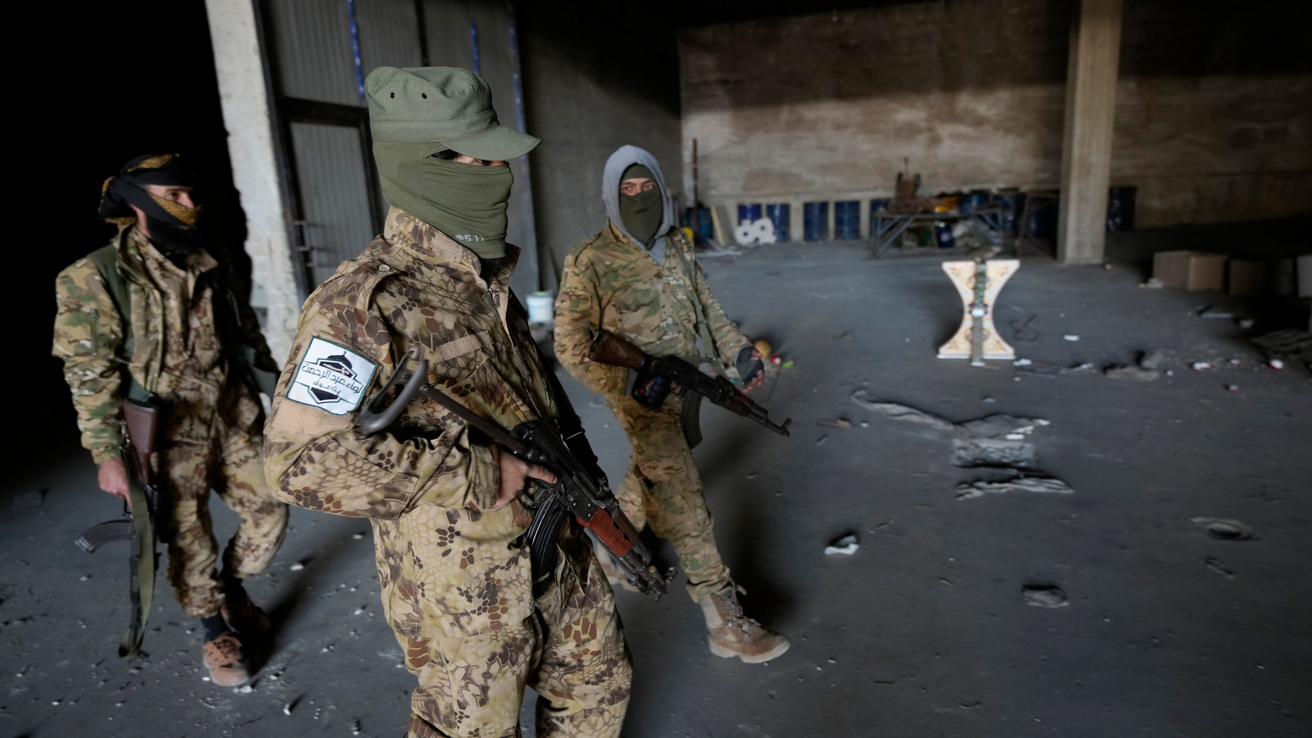 Syrian members of the rebel group walk at a warehouse where the amphetamine pills known as Captagon was manufactured before the fall of Bashar Assad government in Douma city, outskirts of Damascus, Syria, Friday, Dec. 13, 2024. (AP Photo/Hussein Malla)