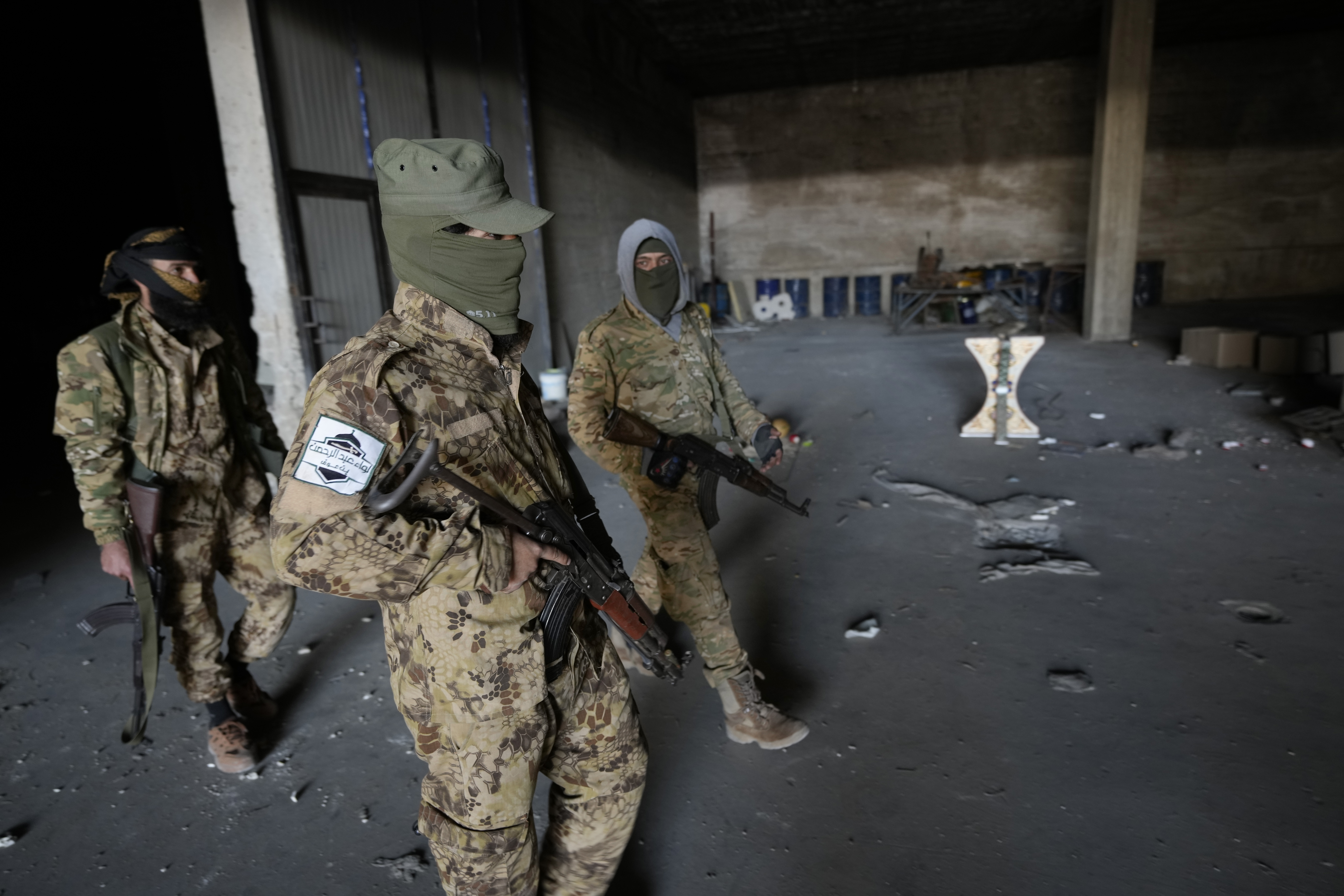 Syrian members of the rebel group walk at a warehouse where the amphetamine pills known as Captagon was manufactured before the fall of Bashar Assad government in Douma city, outskirts of Damascus, Syria, Friday, Dec. 13, 2024. (AP Photo/Hussein Malla)