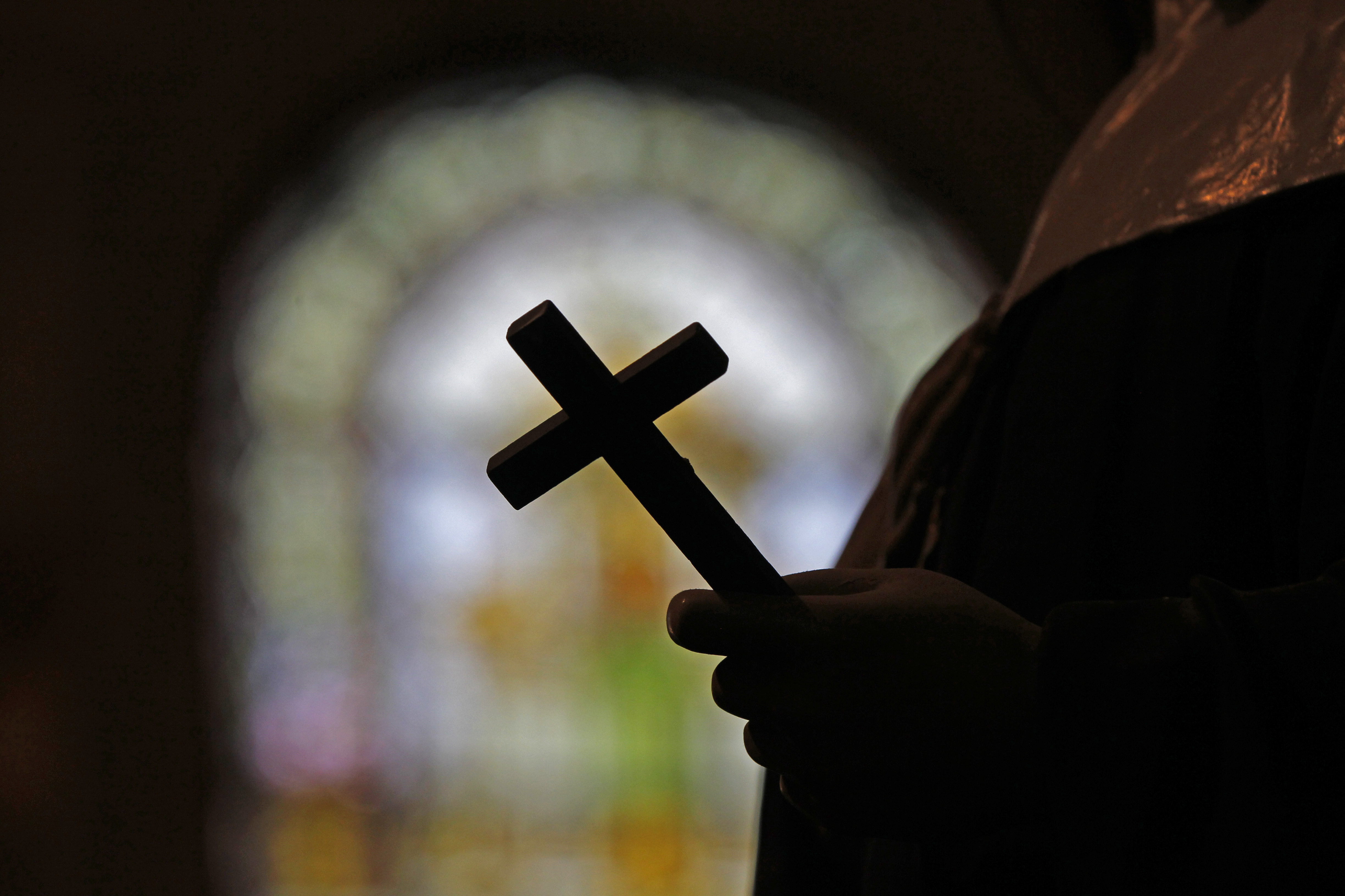 FILE - This Dec. 1, 2012 file photo shows a silhouette of a crucifix and a stained glass window inside a Catholic Church in New Orleans. (AP Photo/Gerald Herbert, File)