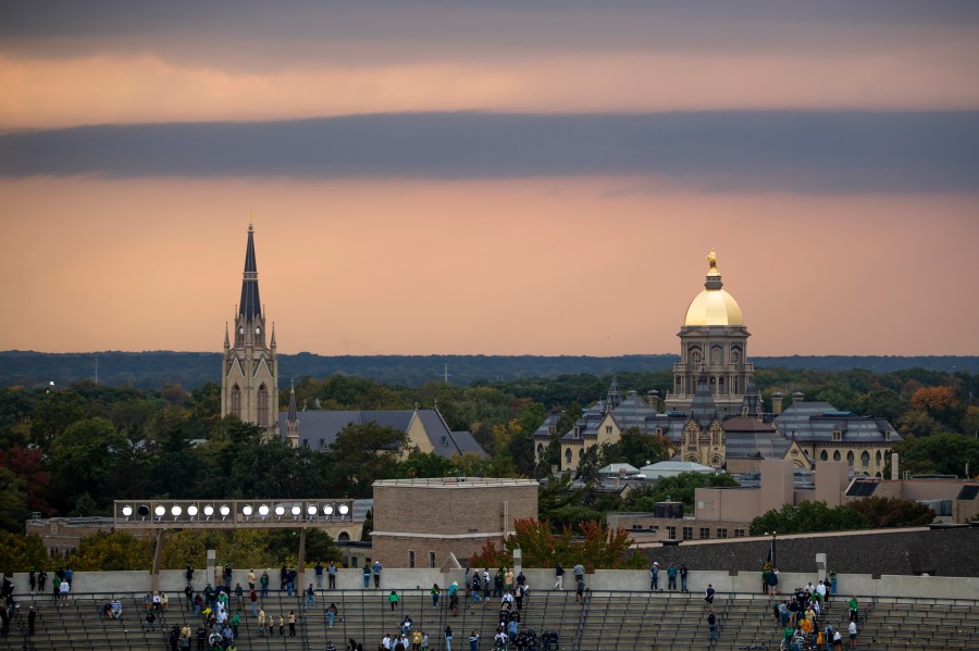 FILE - Fans file out of the stadium as clouds approach the Golden Dome and Basilica of the Sacred Heart on Oct. 12, 2024, in South Bend, Ind. (AP Photo/Michael Caterina, File)