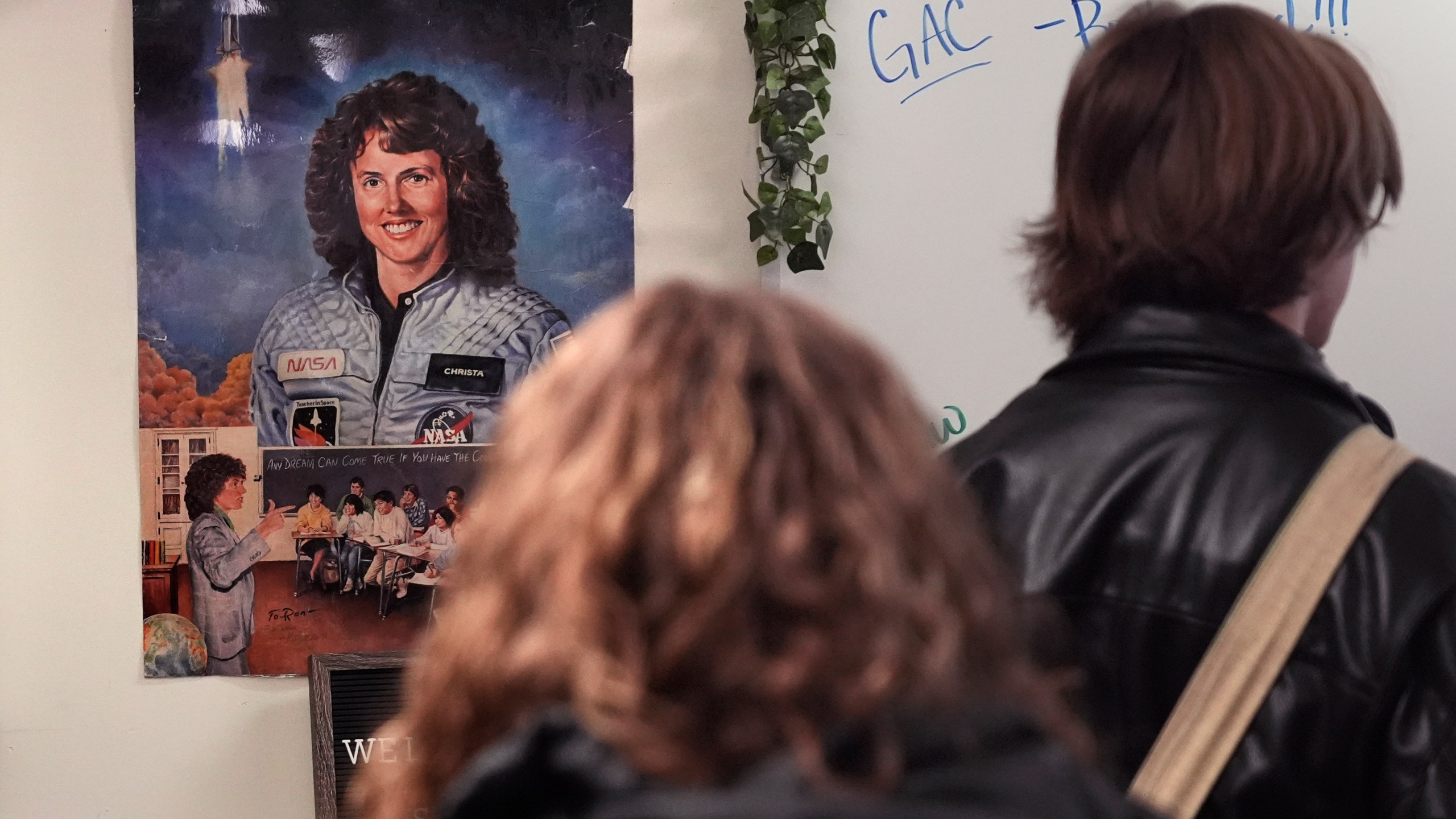 With a poster of NASA's first teacher in space Christa McAuliffe displayed on the wall, students head to their next period class from one of classrooms where McAuliffe taught at Concord High School, Monday, Dec. 16, 2024, in Concord, N.H. (AP Photo/Charles Krupa)