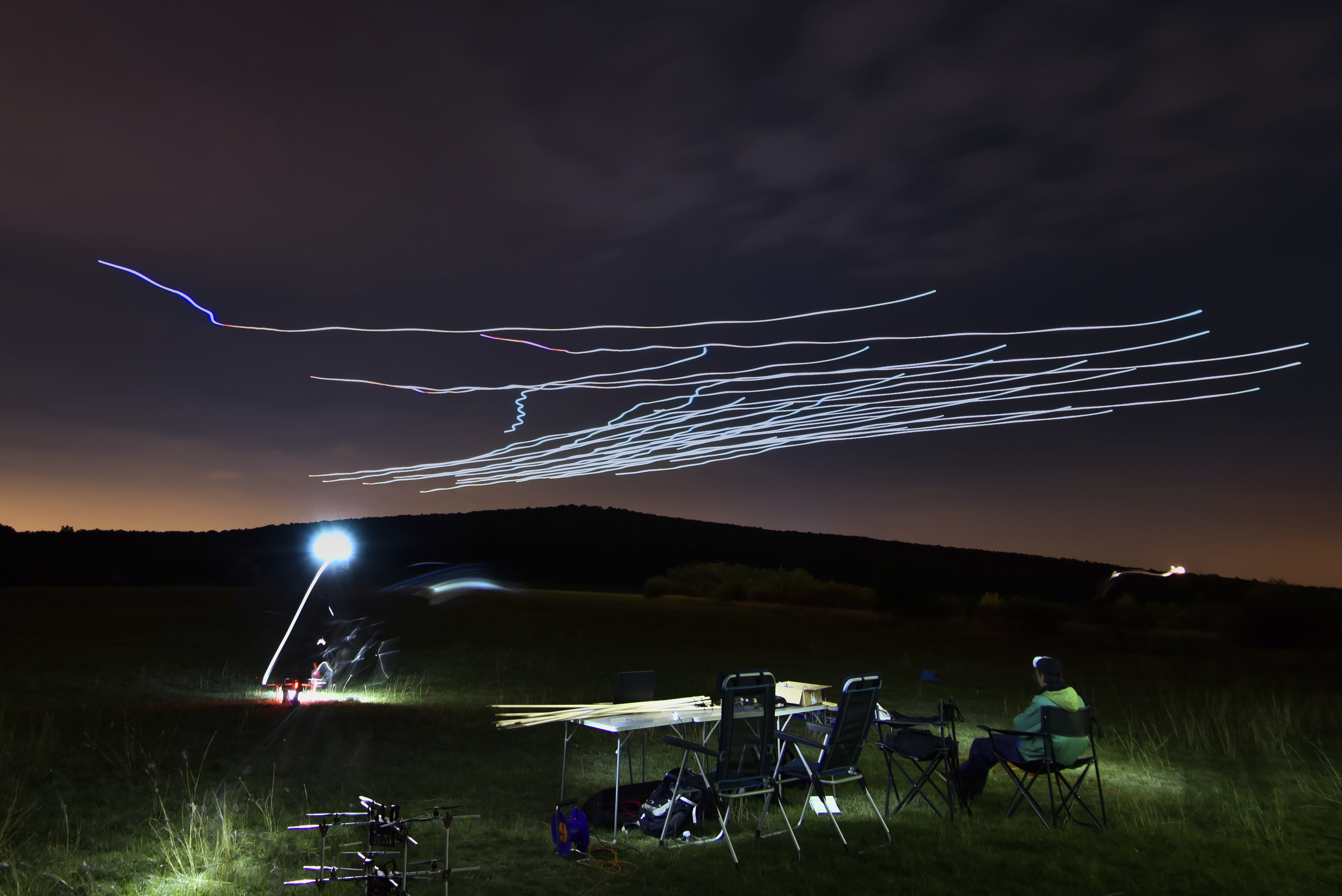 This handout photo taken with long exposure shows a researcher of the Eötvös Loránd University observing the flight of a flock of autonomous drones during an experiment near Budapest, Hungary, Thursday, Oct. 21, 2021. (AP Photo/HO/Eotvos Lorand University)