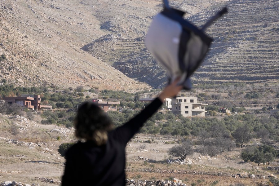 Salma Safadi waves to her sister, Sawsan, who is inside the buffer zone near the "Alpha Line" that separates the Israeli-controlled Golan Heights from Syria, in the town of Majdal Shams, Tuesday, Dec. 17, 2024. (AP Photo/Matias Delacroix)