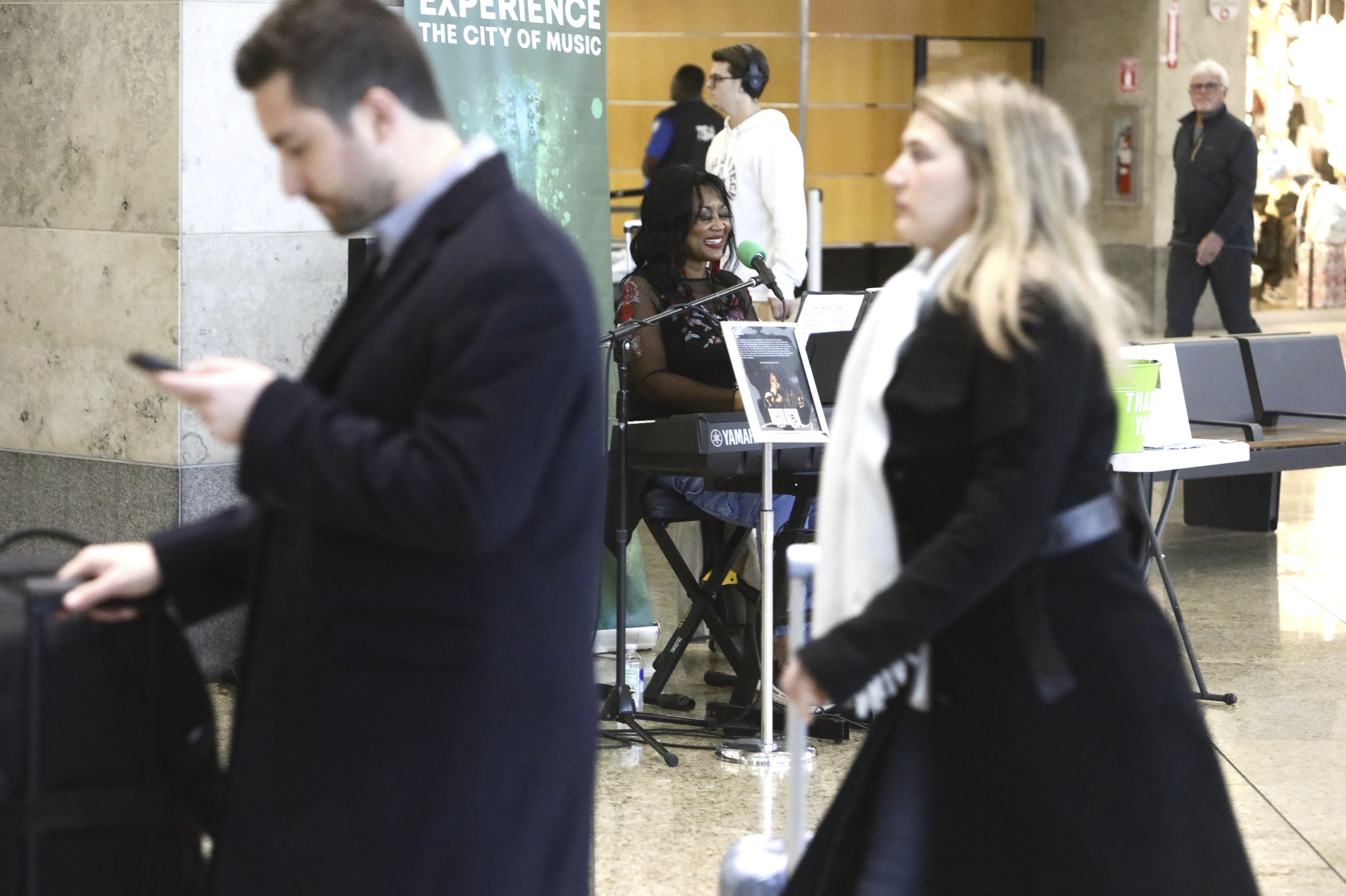 Roz McCommon, center, performs amid travelers at Seattle-Tacoma International Airport on November 26, 2024, in SeaTac, Wash. (AP Photo/Manual Valdes)