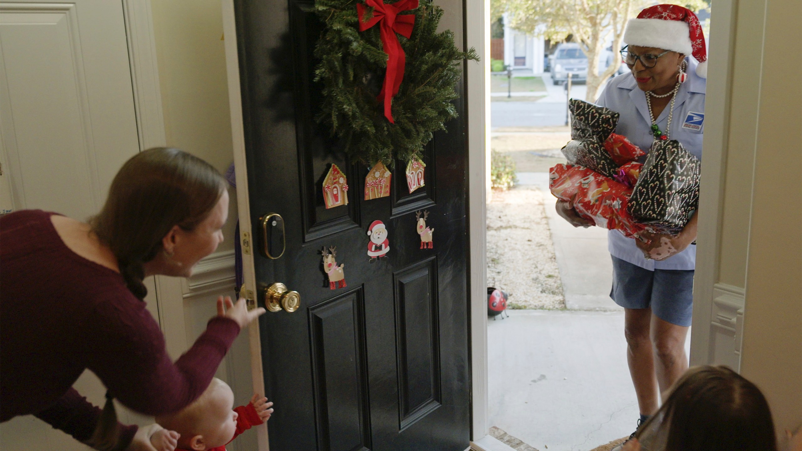 This image released by Disney shows a postal worker, right, delivering gifts to a home in a scene from "Dear Santa, The Series." (Disney via AP)