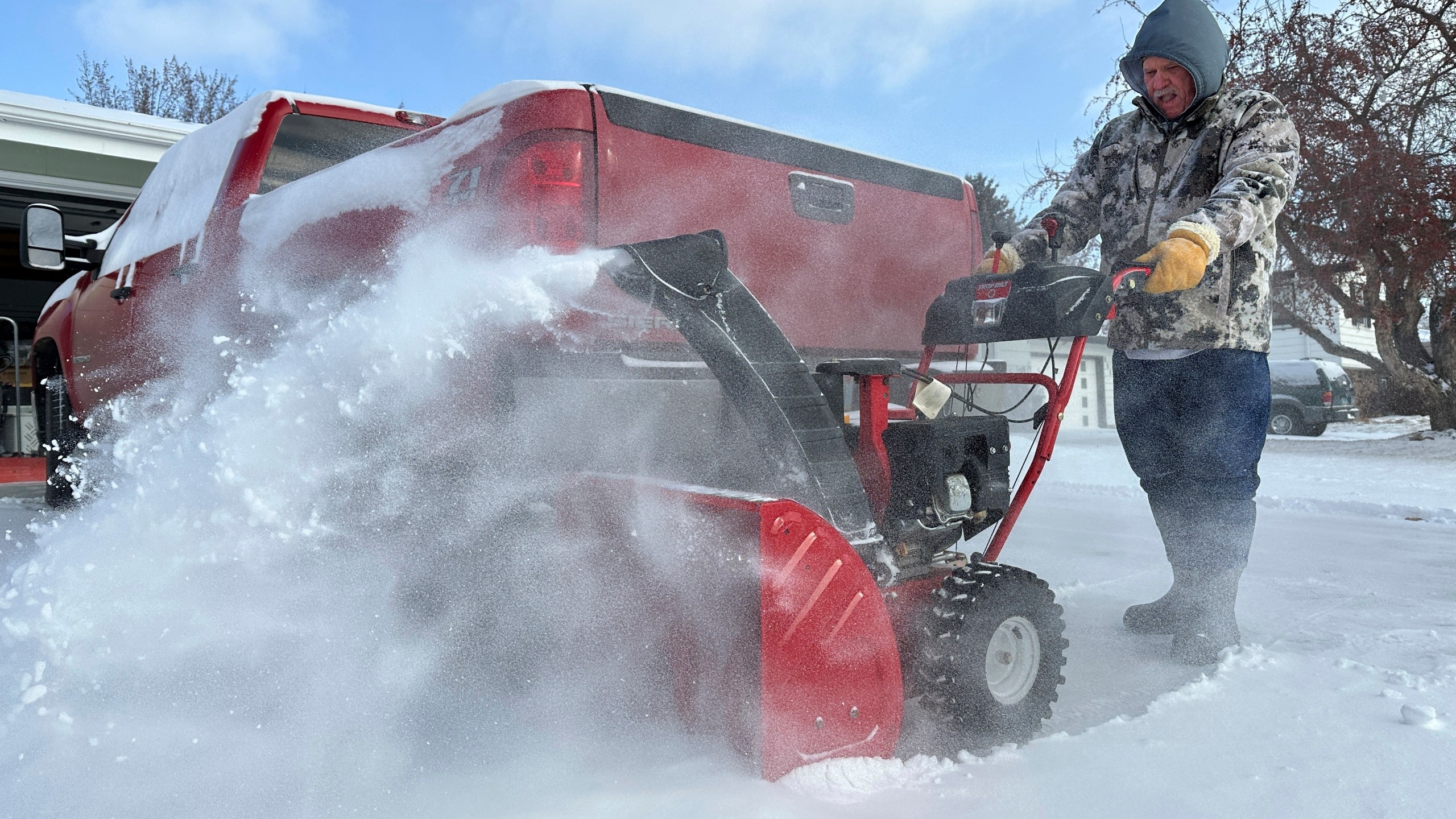 Jim Thom clears his driveway of snow with a snowblower on Thursday, Dec. 19, 2024, in Bismarck, N.D. (AP Photo/Jack Dura)