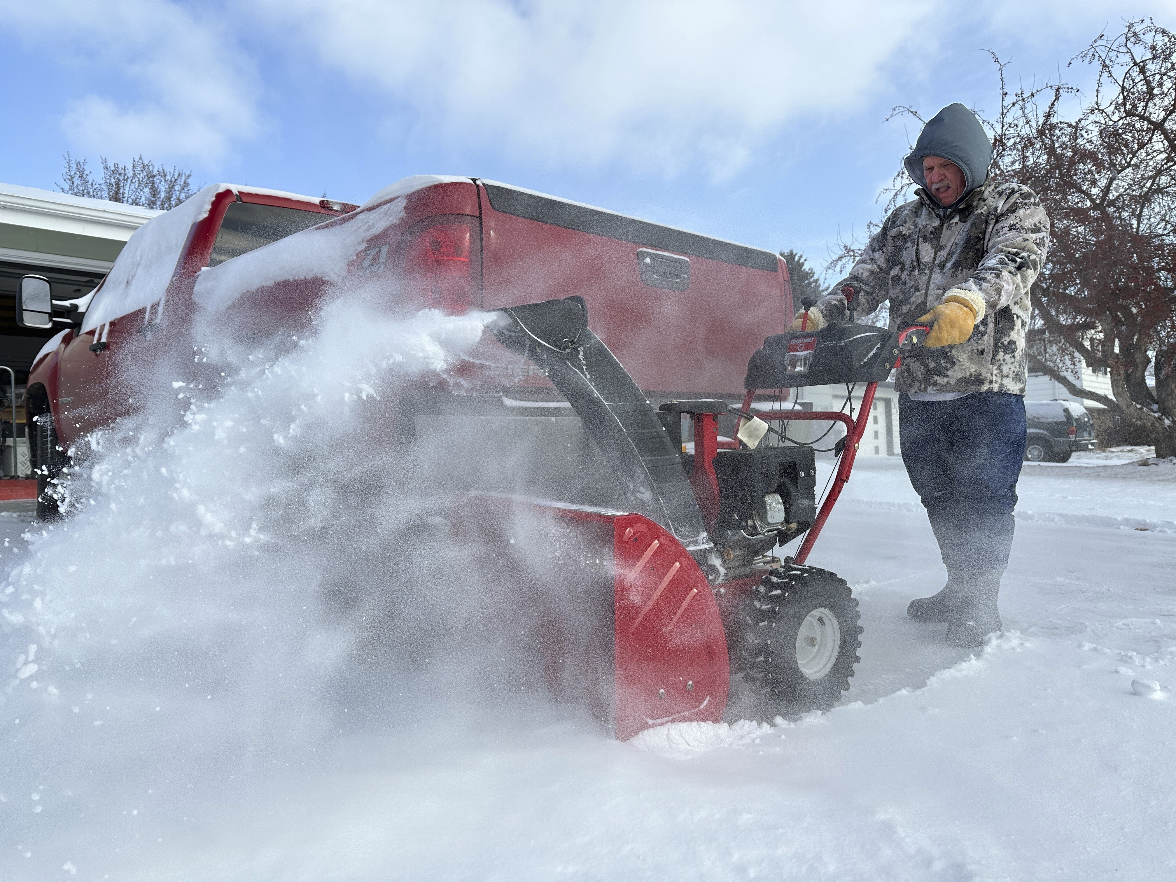 Jim Thom clears his driveway of snow with a snowblower on Thursday, Dec. 19, 2024, in Bismarck, N.D. (AP Photo/Jack Dura)