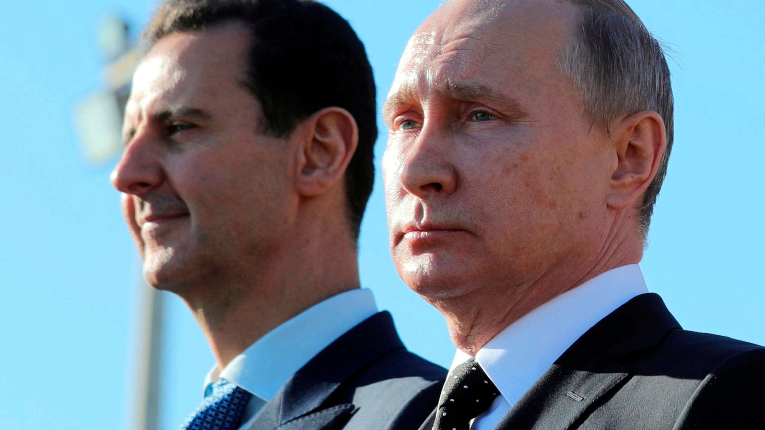 FILE - Russian President Vladimir Putin, right, and Syrian President Bashar Assad watch troops at the Hemeimeem air base in Syria, on Dec. 11, 2017. (Mikhail Klimentyev, Sputnik, Kremlin Pool Photo via AP, File)