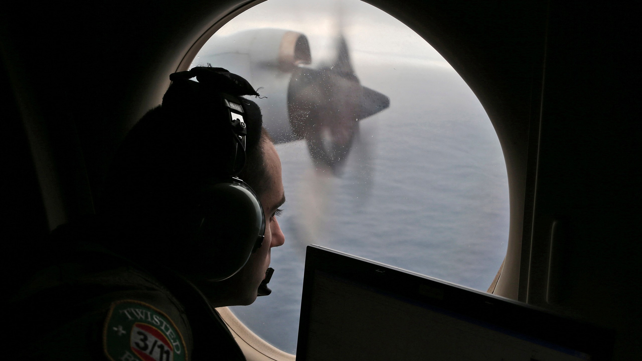 FILE - Flight officer Rayan Gharazeddine scans the water in the southern Indian Ocean off Australia from a Royal Australian Air Force AP-3C Orion during a search for the missing Malaysia Airlines Flight MH370, March 22, 2014. (AP Photo/Rob Griffith, File)