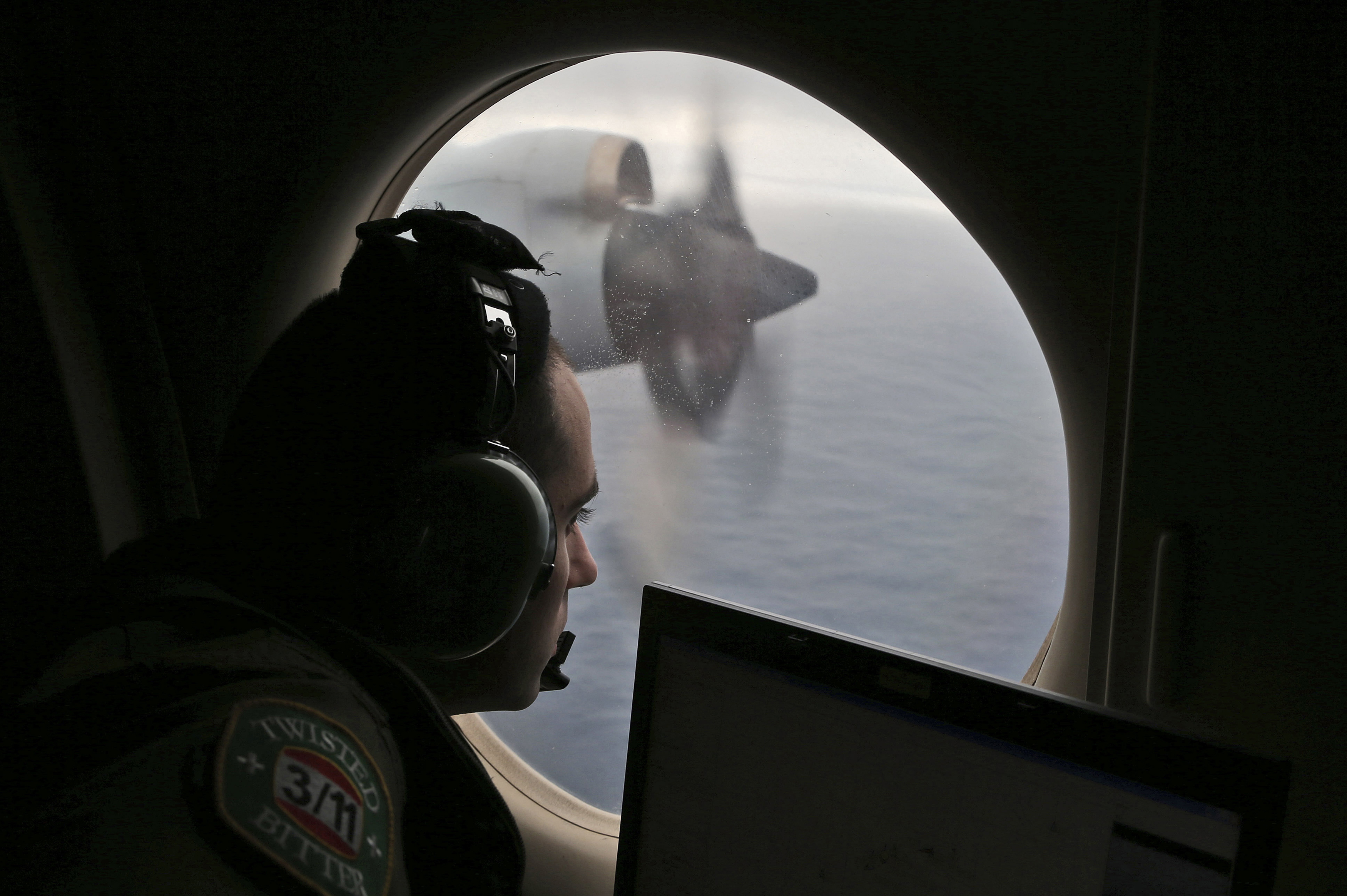 FILE - Flight officer Rayan Gharazeddine scans the water in the southern Indian Ocean off Australia from a Royal Australian Air Force AP-3C Orion during a search for the missing Malaysia Airlines Flight MH370, March 22, 2014. (AP Photo/Rob Griffith, File)