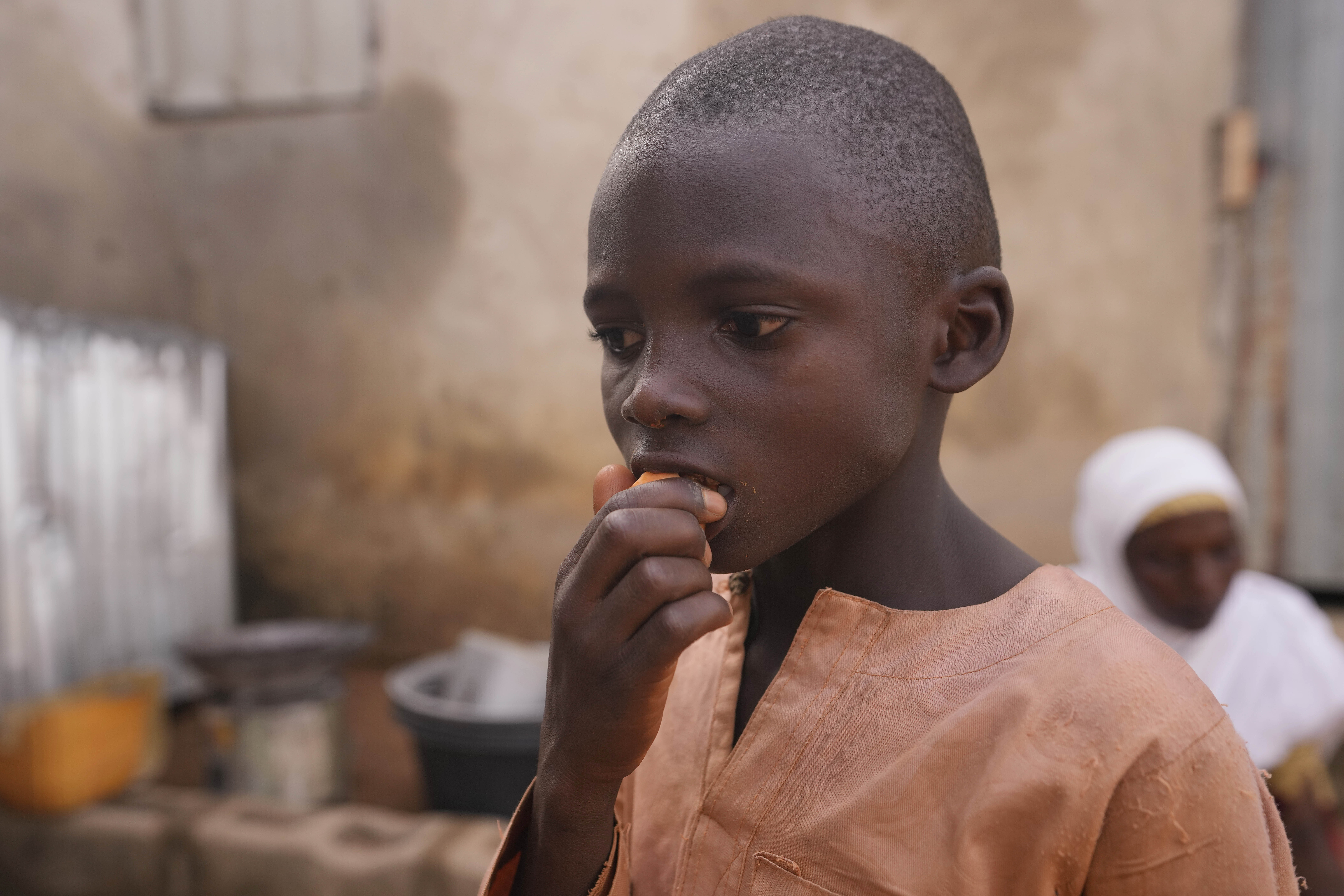 FILE - Hauwa Bwami's grandson Suleiman eats an orange-fleshed sweet potato, harvest from a farm inside their compound in Kaltungo Poshereng Nigeria, Sunday, June 2, 2024. (AP Photo/Sunday Alamba, File)