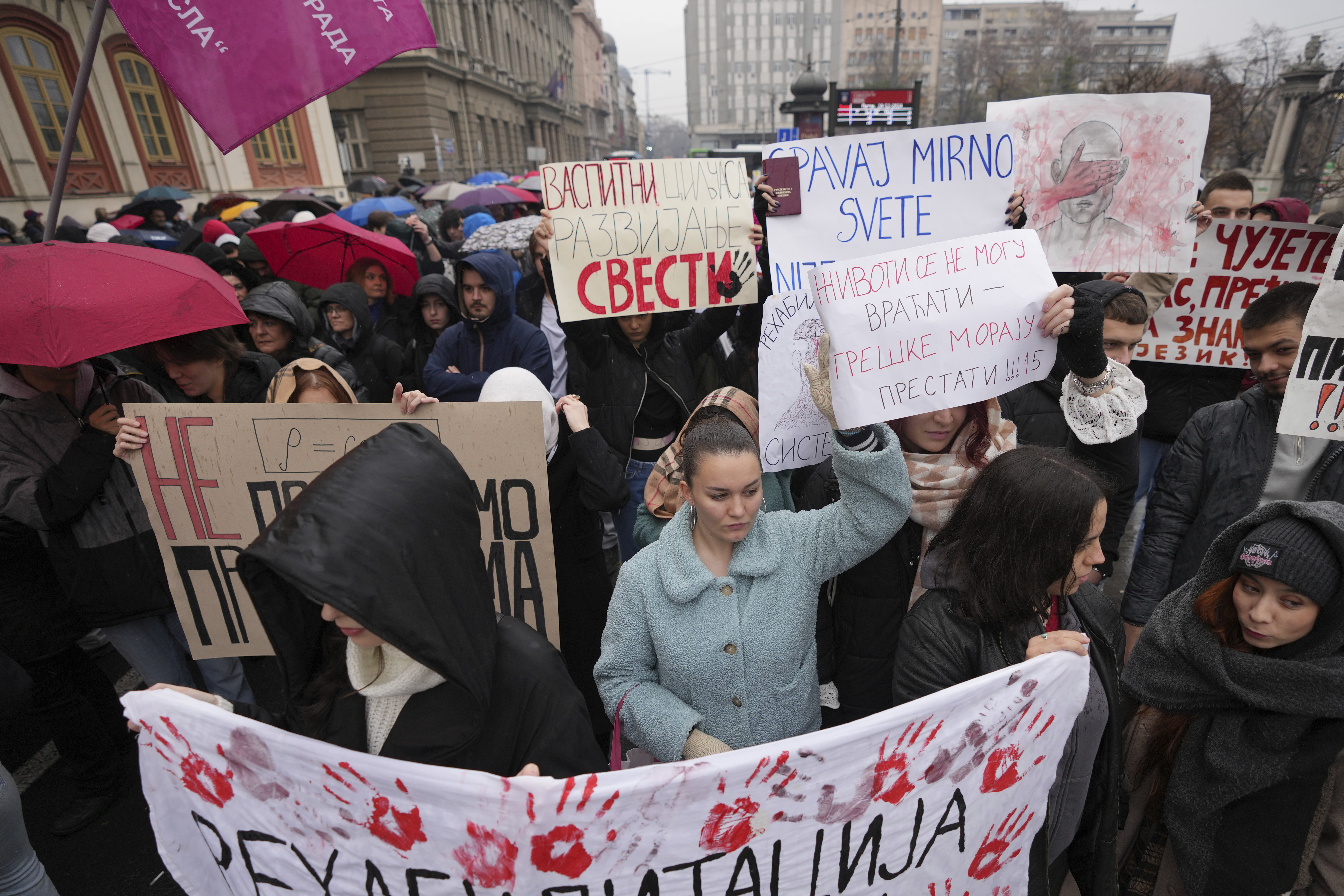 People stopping traffic, stand in silence during ongoing protests that erupted after a concrete canopy fell last month and killed 15 people, in Belgrade, Serbia, Friday, Dec. 20, 2024. (AP Photo/Darko Vojinovic)