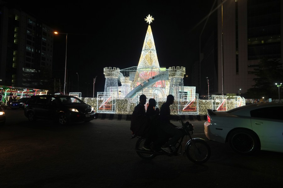 A man rides a motorcycle taxi past Christmas decorations on a street in Lagos, Nigeria, Friday, Dec. 20, 2024. (AP Photo/Sunday Alamba)